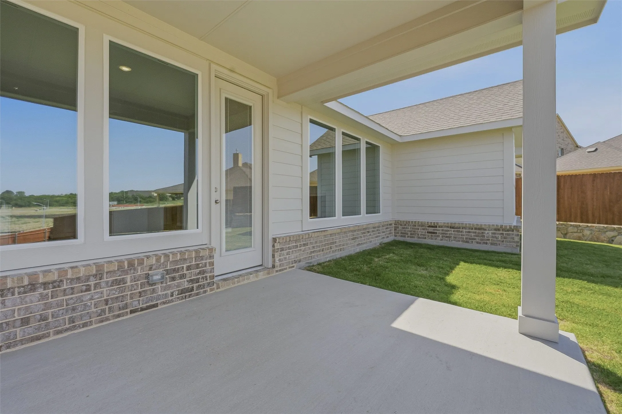 Covered patio featuring a concrete surface, column support, and a brick facade