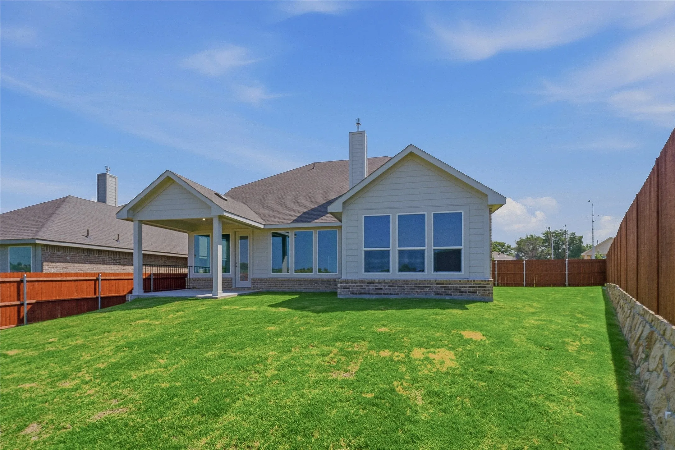 Expansive backyard featuring a manicured lawn, a covered patio, and a privacy fence