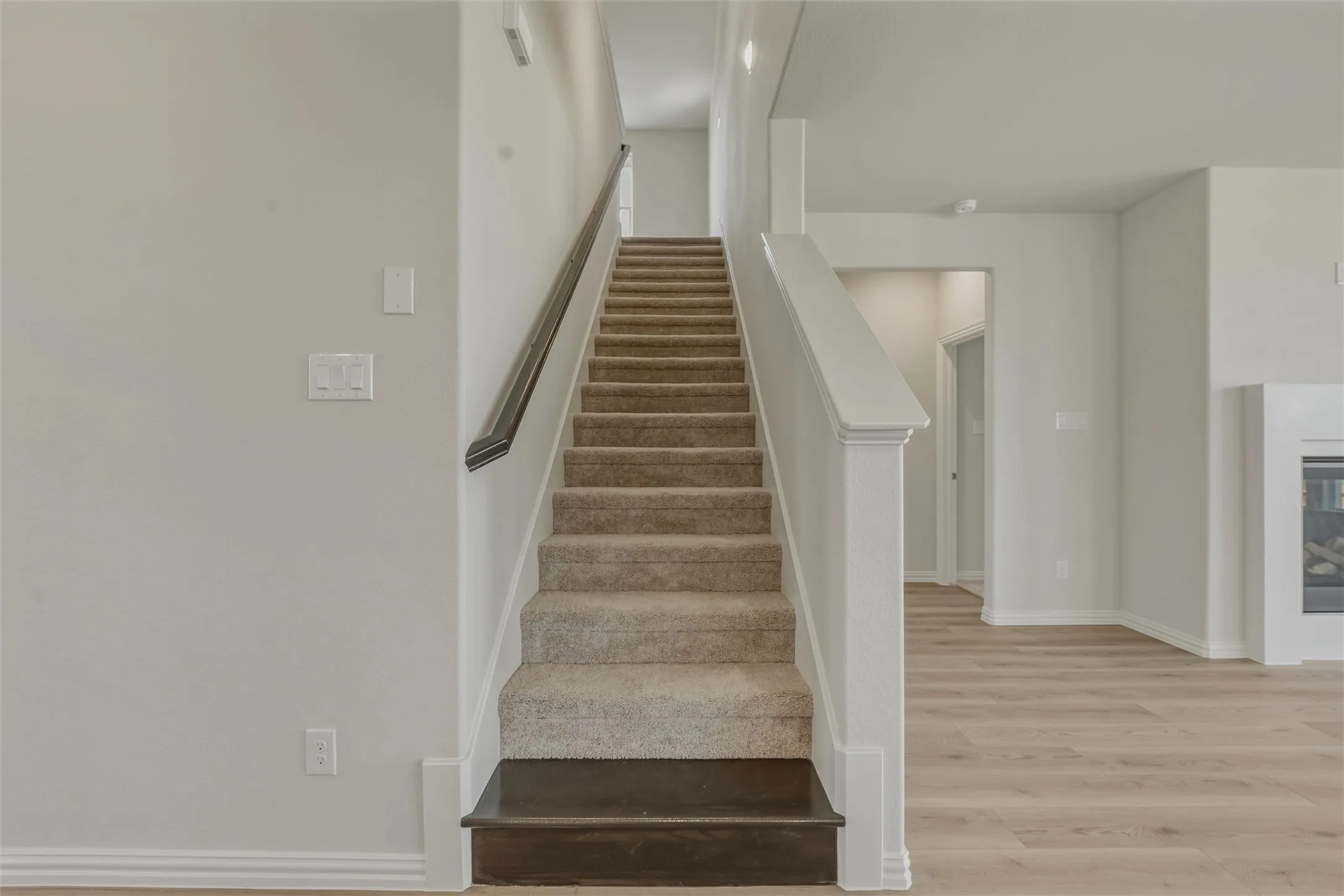 Carpeted staircase with dark wood-finish handrail and newel post