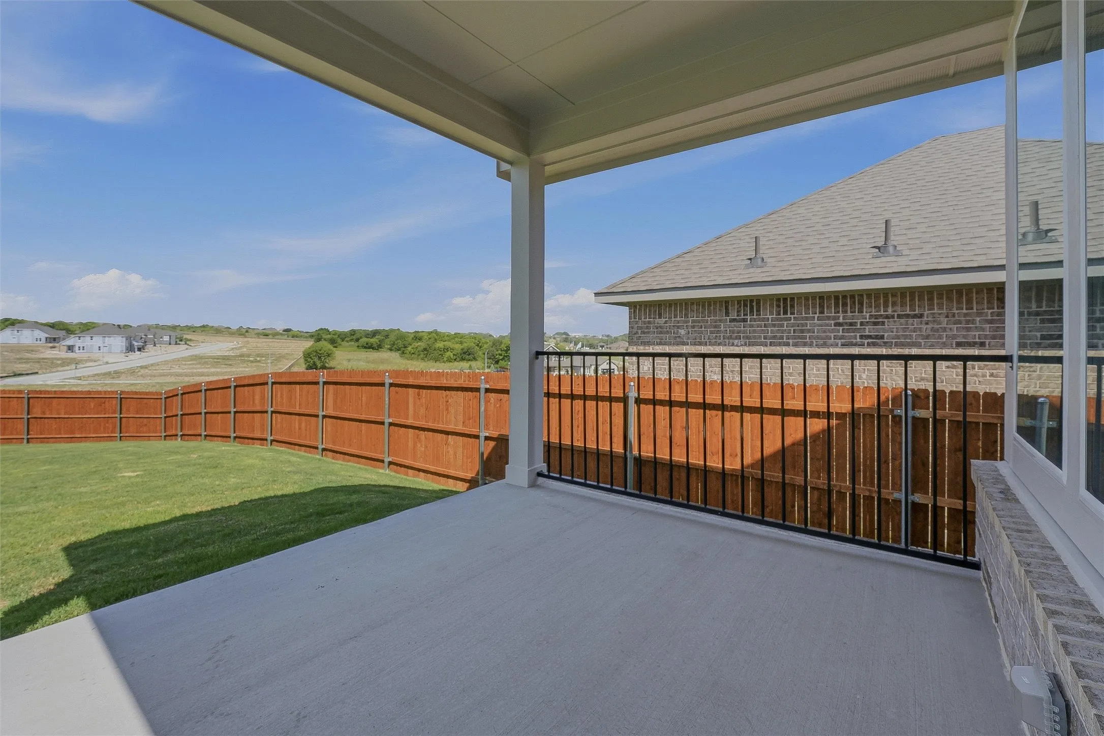 Covered patio featuring a concrete surface, white columns, and a black metal railing