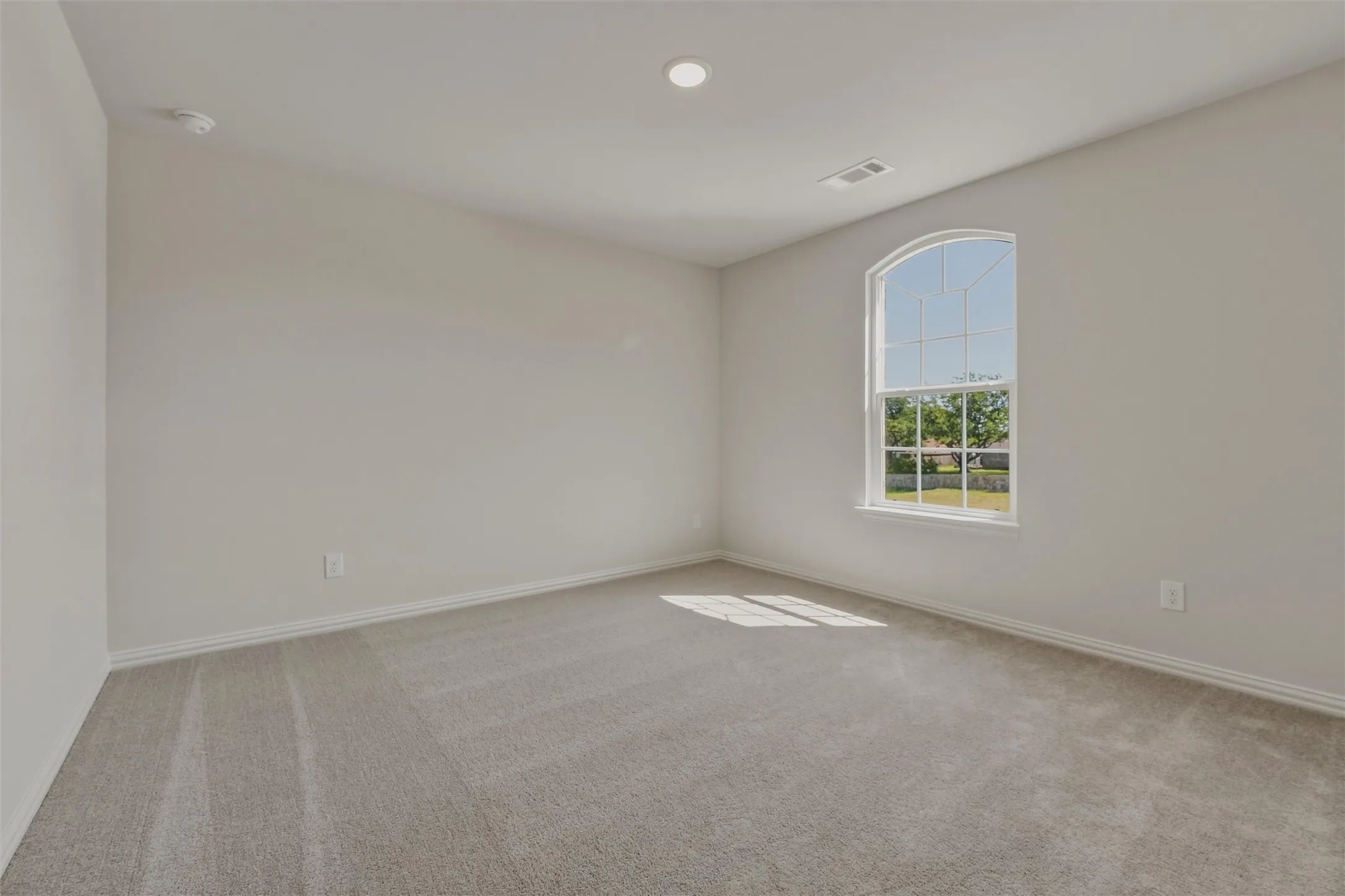 Carpeted room featuring a large arched window, recessed ceiling lighting, and light-toned wall finishes