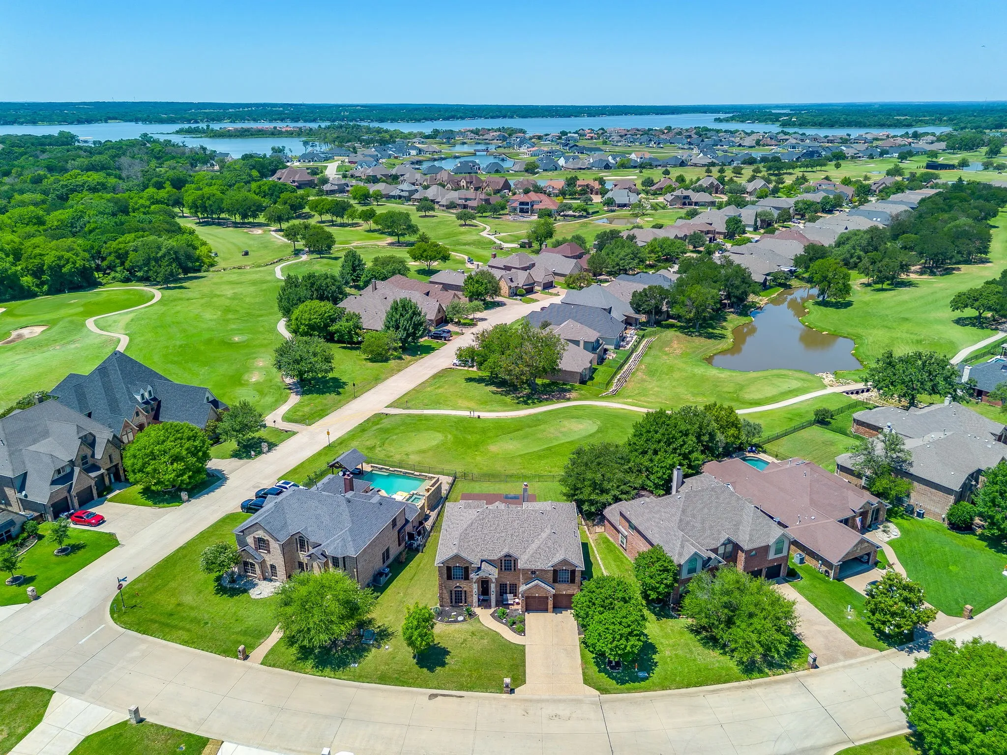 Expansive residential community with diverse architectural styles, featuring direct golf course access, extensive green spaces, a private pond, and proximity to a large body of water