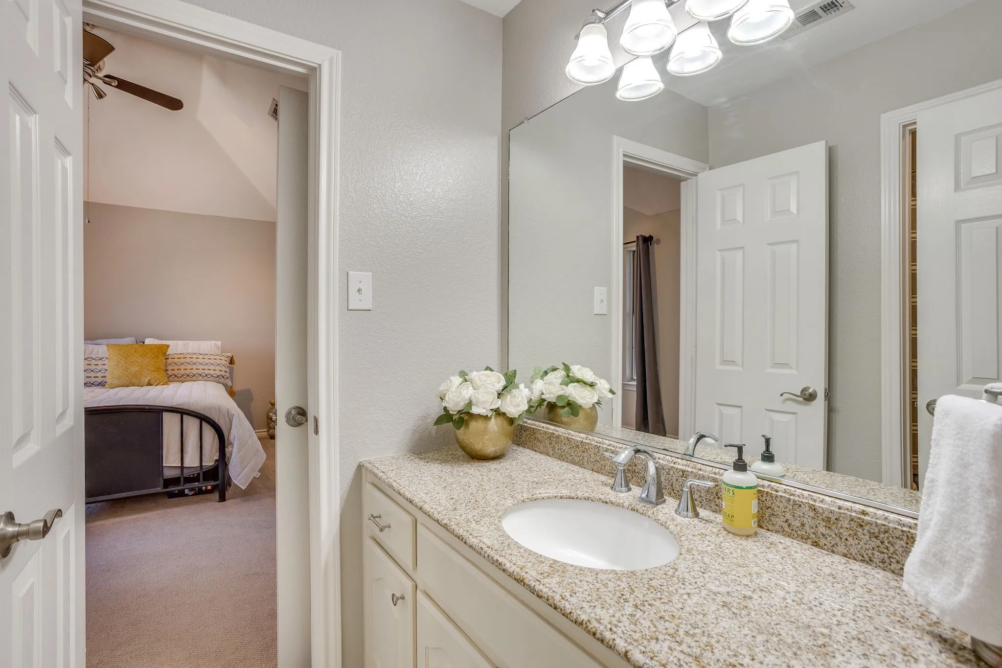 Bathroom vanity featuring a speckled countertop, undermount sink, and chrome faucet