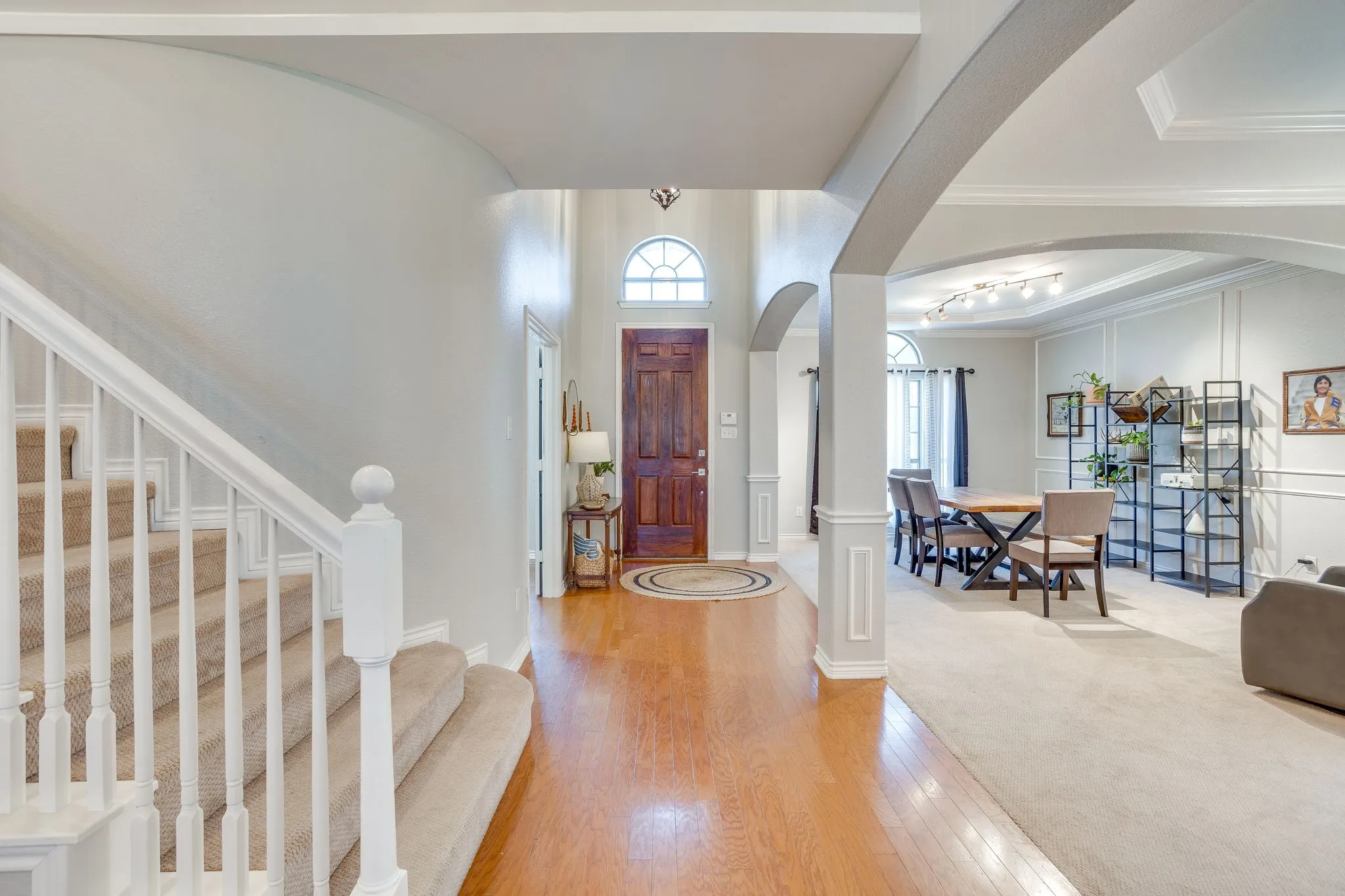 Foyer entry featuring wood-finish flooring, a two-story ceiling, and an arched transom window above the front door