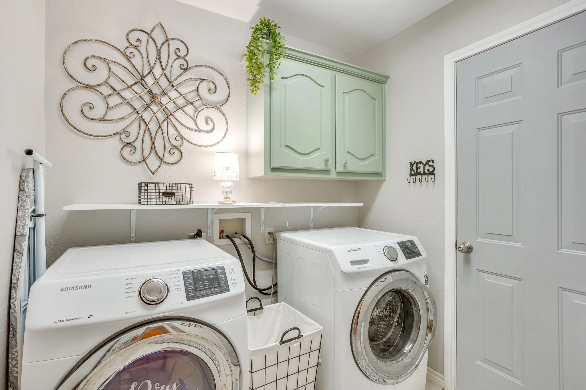 Laundry area featuring light green cabinetry, a paneled door, and an overhead shelf