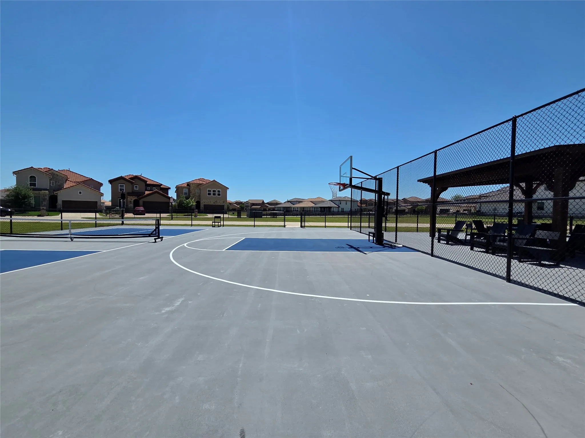 Multi-sport court featuring a basketball hoop, white court lines, and blue-painted sections