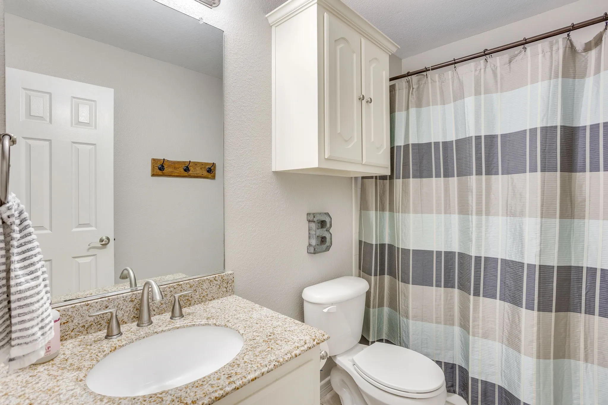 Bathroom featuring a granite-look countertop, undermount sink, and brushed nickel faucet