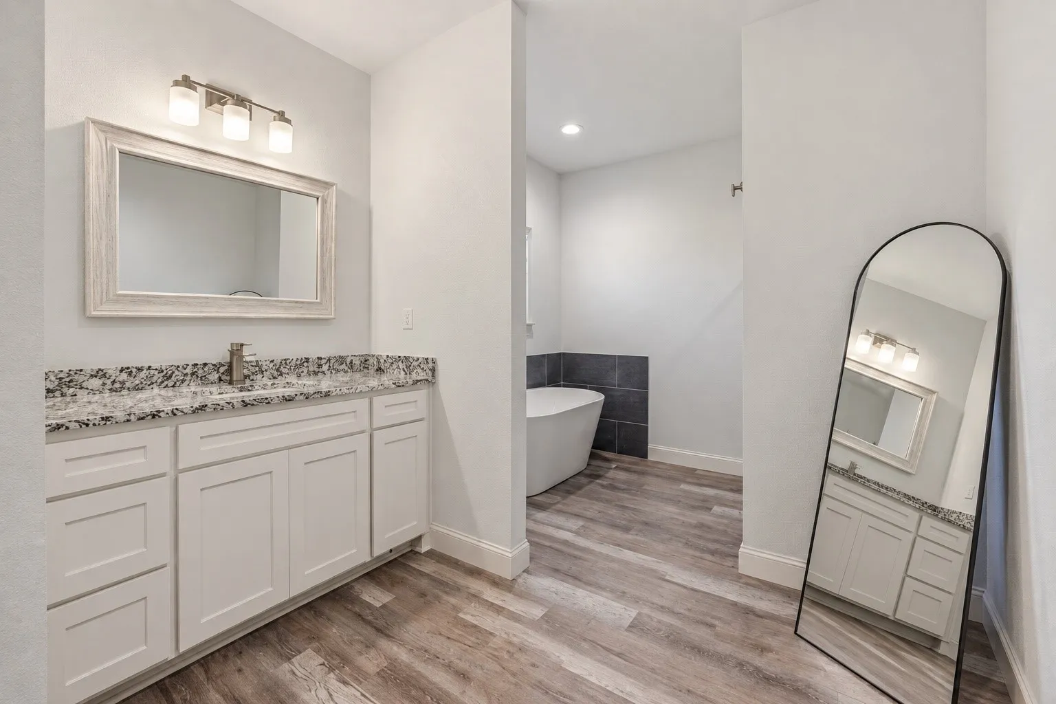 White shaker-style vanity with a speckled countertop, undermount sink, and brushed nickel faucet