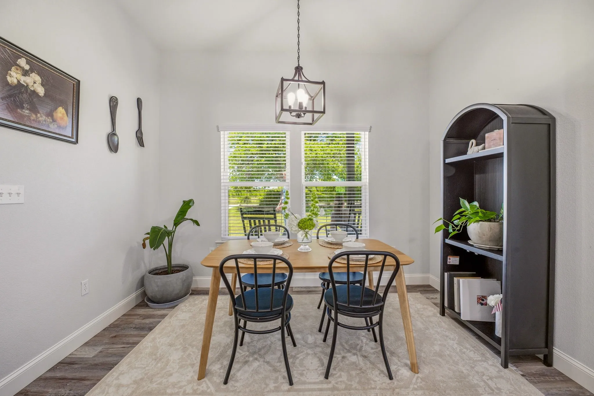 Vaulted ceiling with a contemporary chandelier, wood-finish flooring, and a large window with horizontal blinds