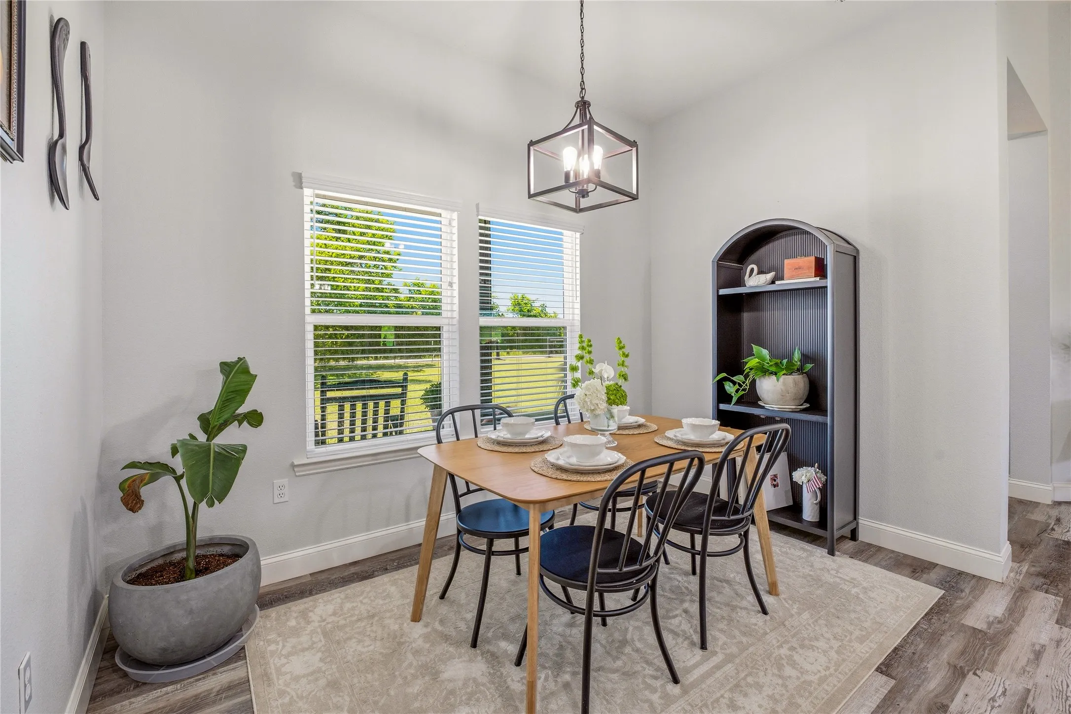 Dining area featuring a contemporary overhead light fixture, wood-finish flooring, and two windows with blinds