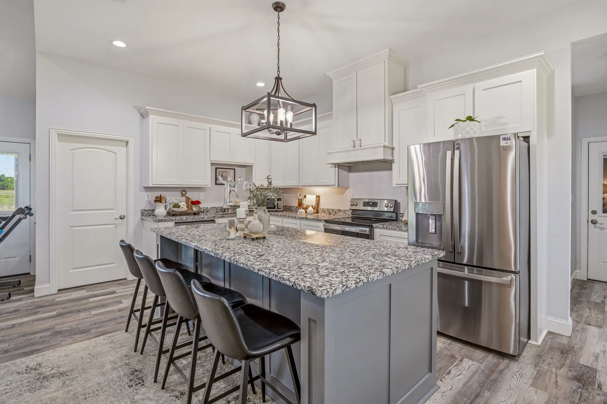 Kitchen featuring a central island with countertop seating, white upper cabinetry, stainless steel appliances, and wood-finish flooring