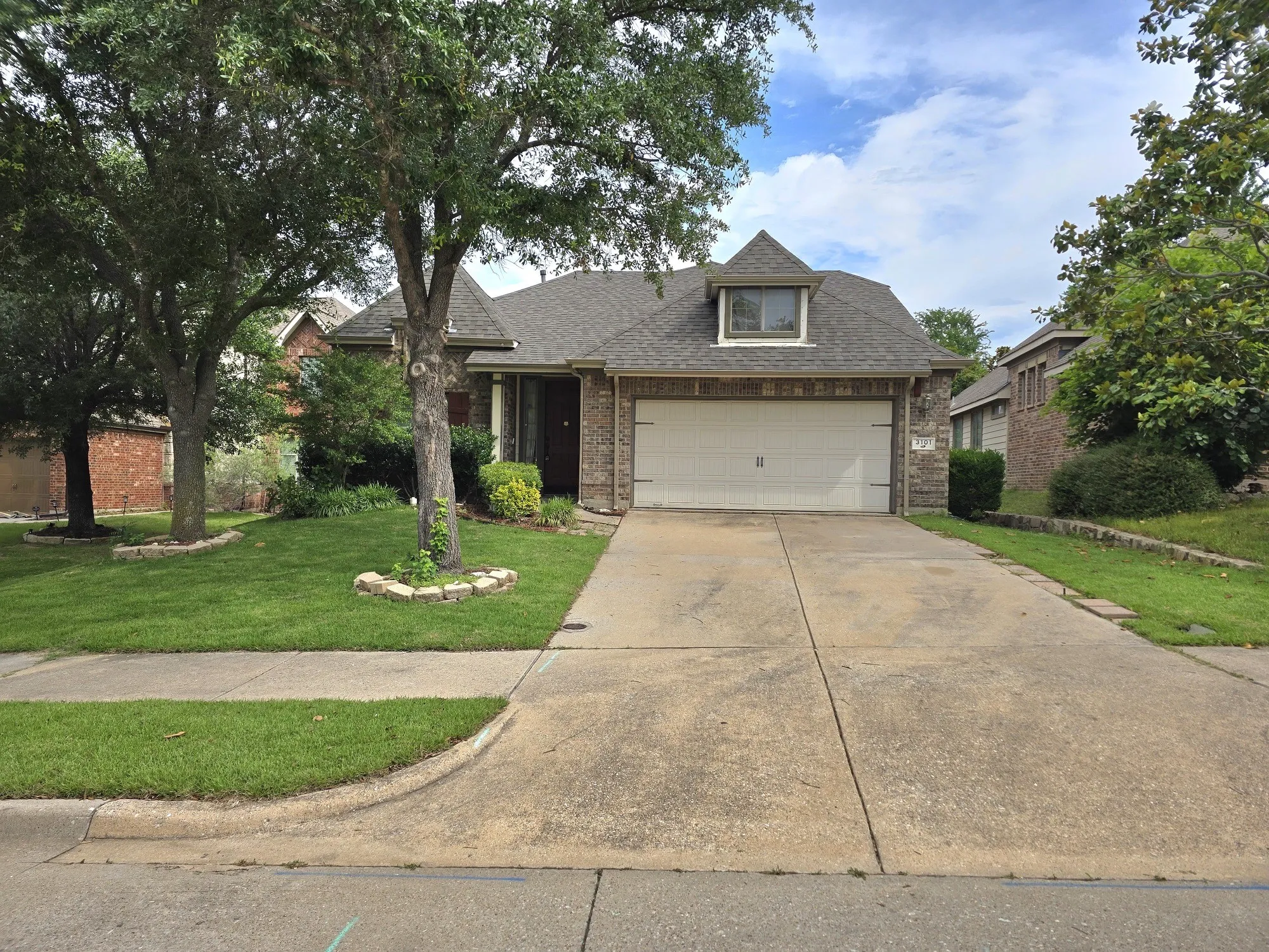 Traditional brick exterior with a two-car garage, dormer window, and a gabled roofline
