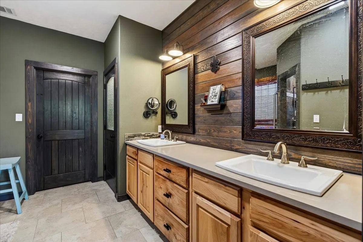 Primary1 Ensuite bath with Dual vanity with light wood cabinetry, white rectangular sinks, and brushed gold fixtures