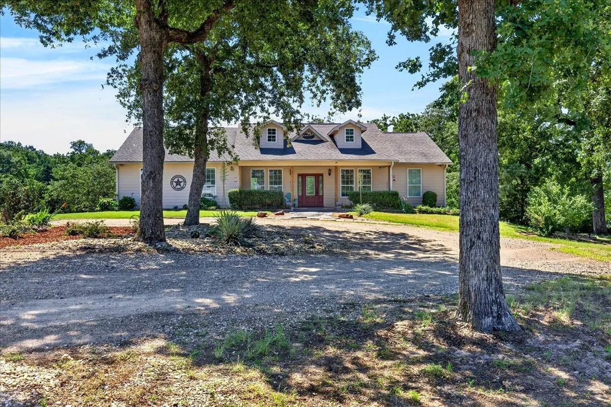 Traditional-style residence featuring a dormer roofline, covered porch, and a gravel driveway