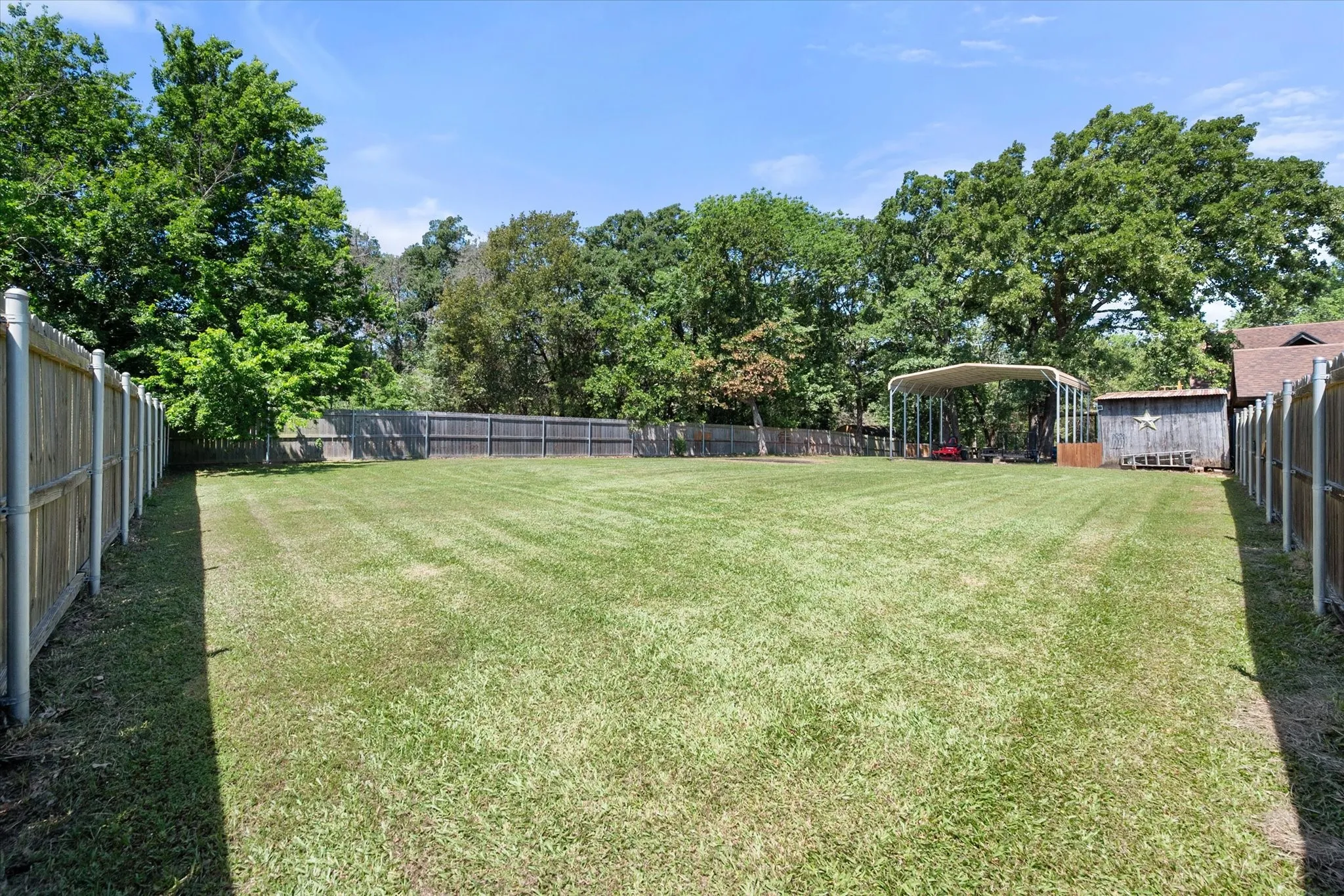 Large level backyard shaded by mature trees on approximately 0.69 acres.