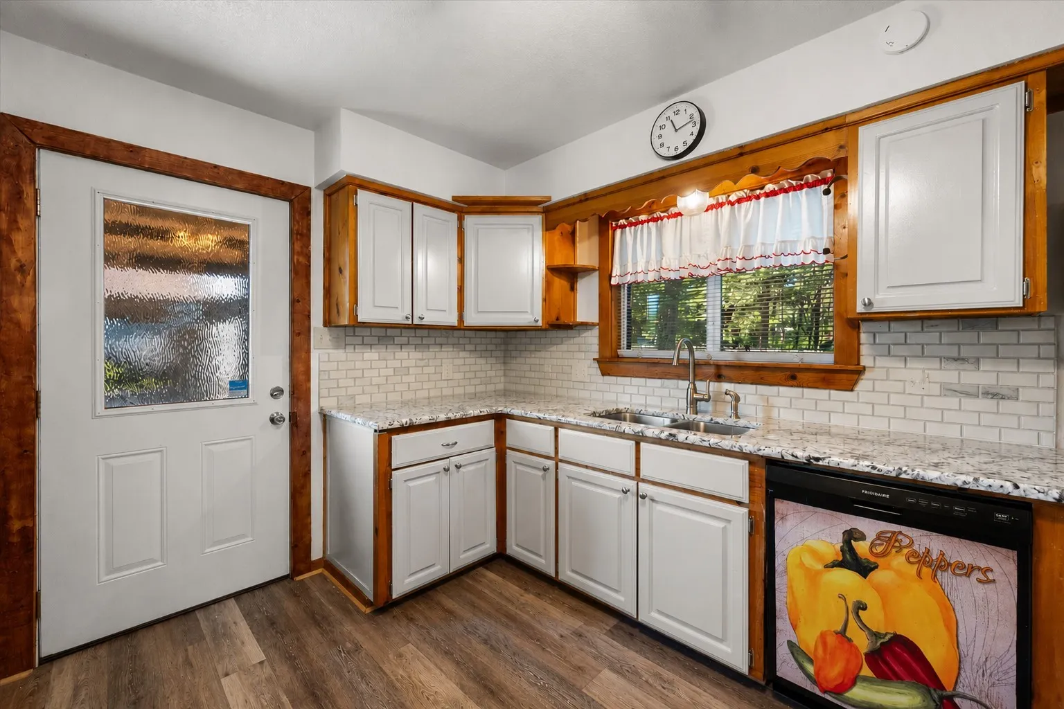 Updated kitchen with granite countertops, subway tile backsplash, and backyard access.