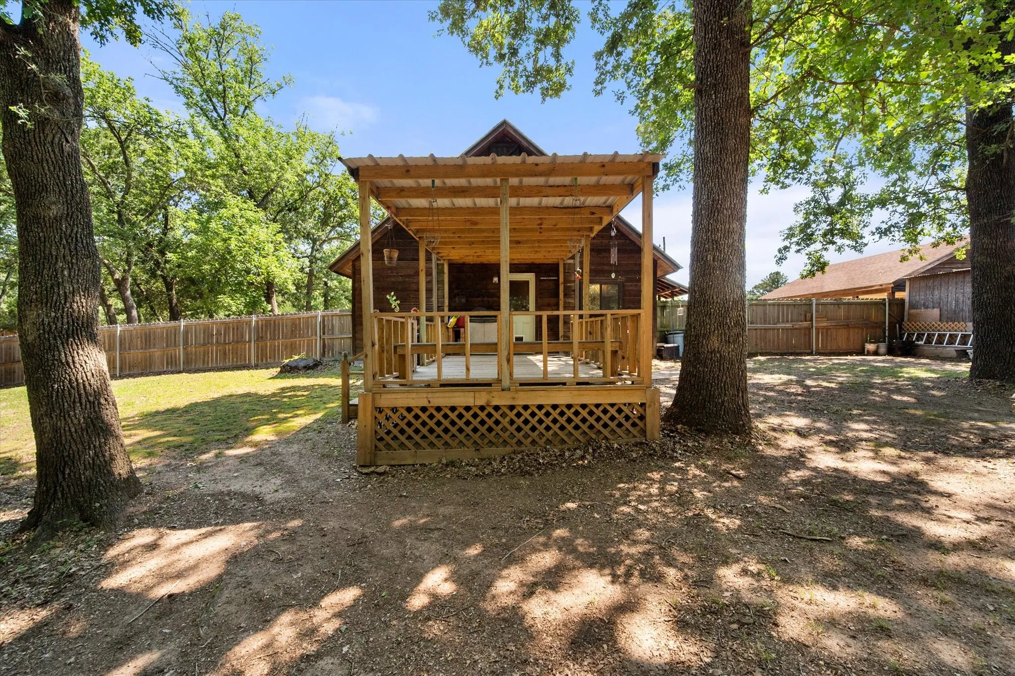 Rear view showcases spacious fenced backyard and covered entertaining deck.