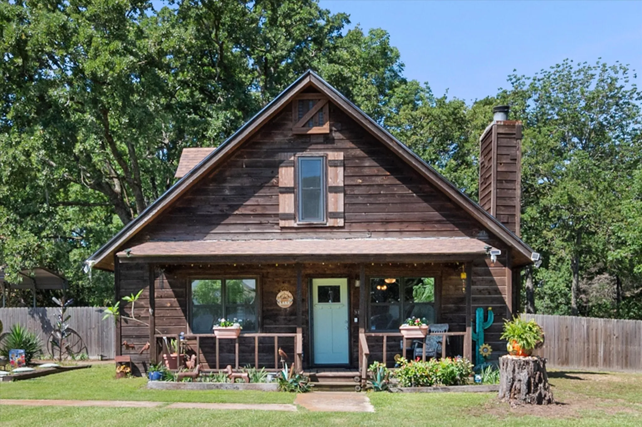 Front exterior showcases covered porch, balcony, and peaceful wooded setting.