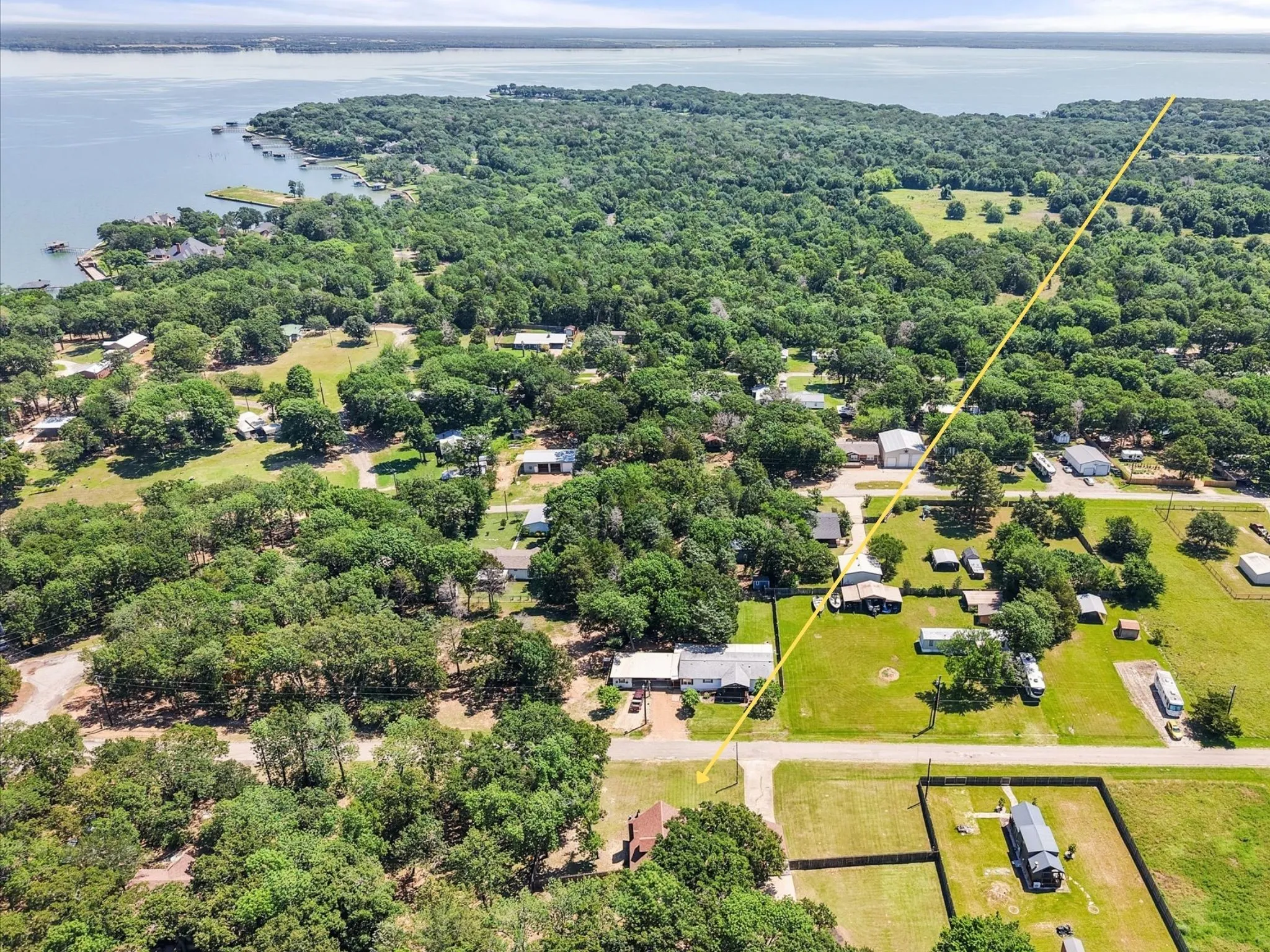 Elevated aerial showcasing wooded surroundings and convenient lake community location.