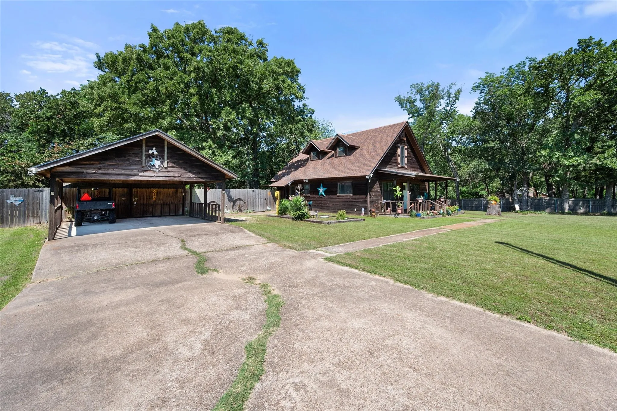 Long driveway leads to charming cabin-style home with detached two-car carport and RV parking.