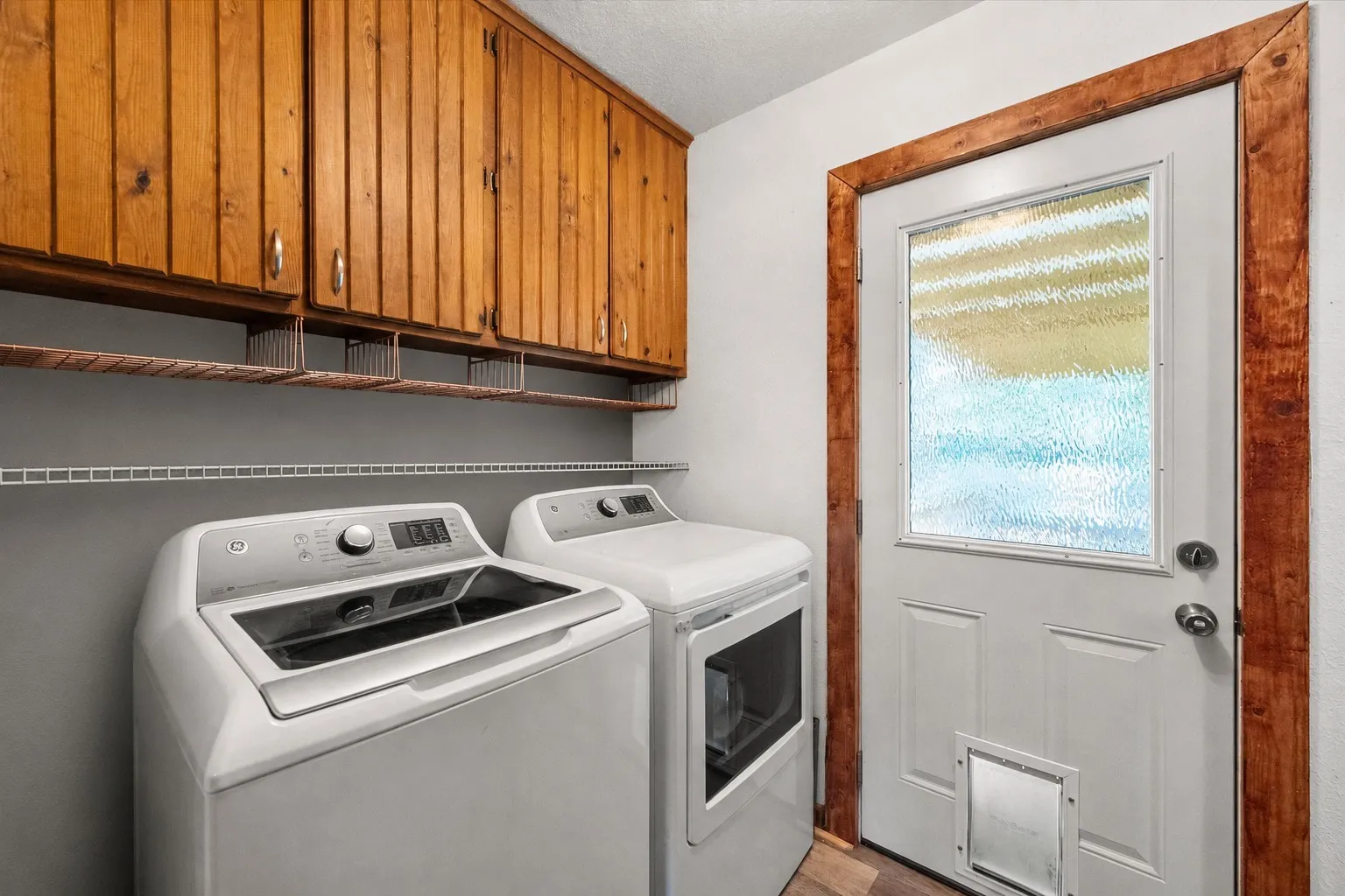 Laundry room with full-size washer and dryer plus abundant built-in storage cabinets.