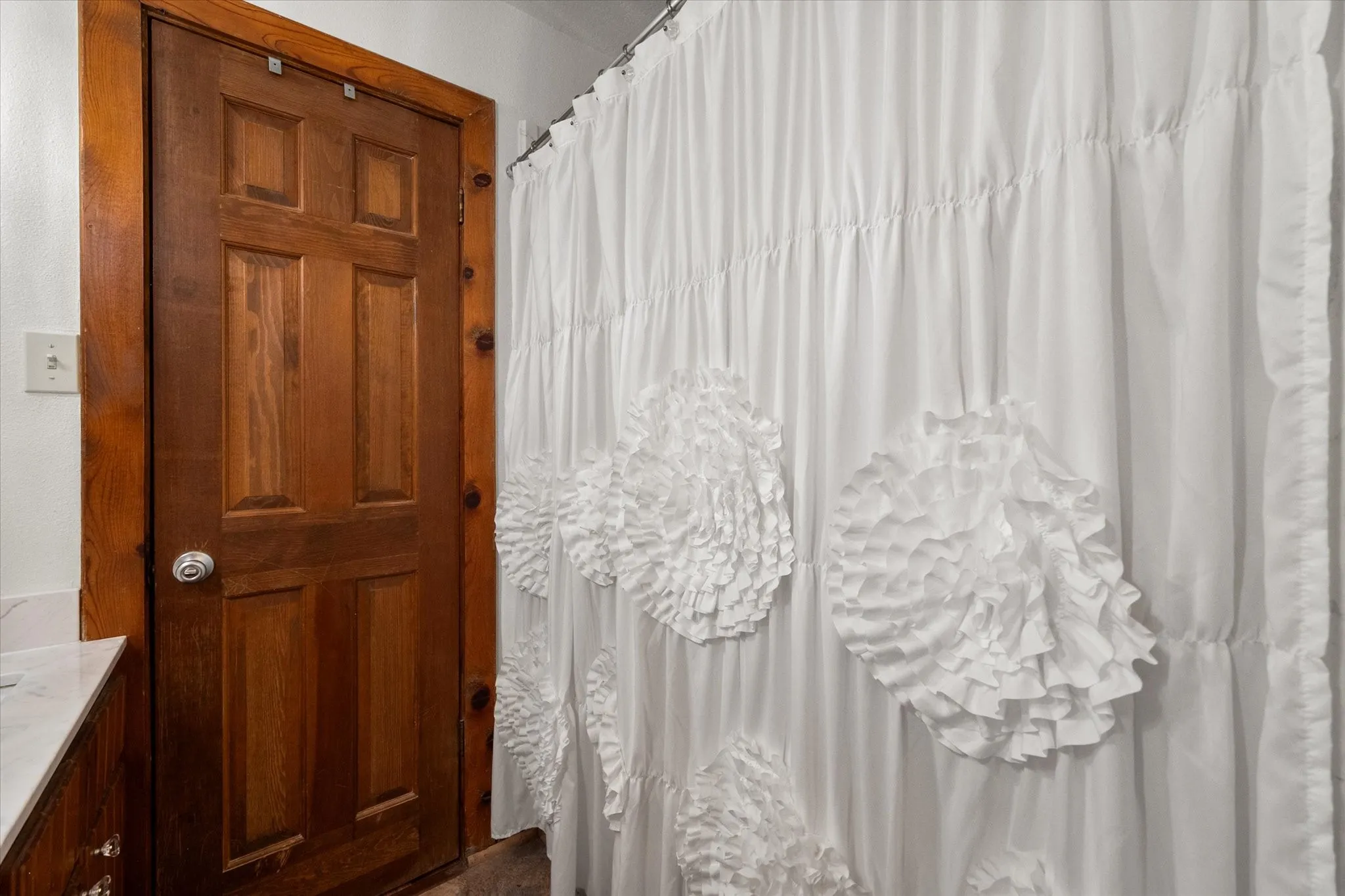 Walk-in shower with decorative curtain and updated finishes.