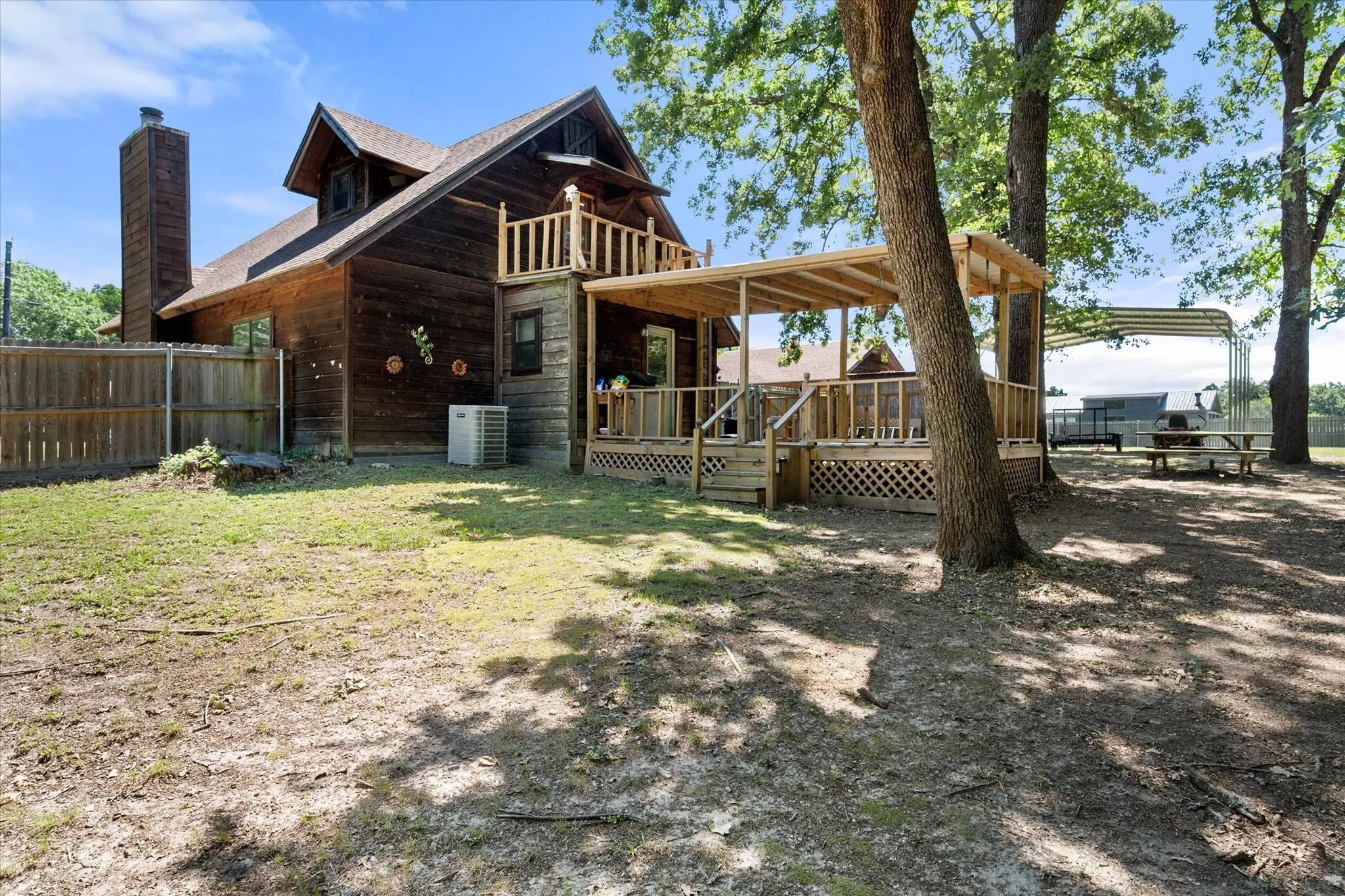 Side exterior highlights covered porch, wraparound deck, and spacious corner lot shaded by mature trees.