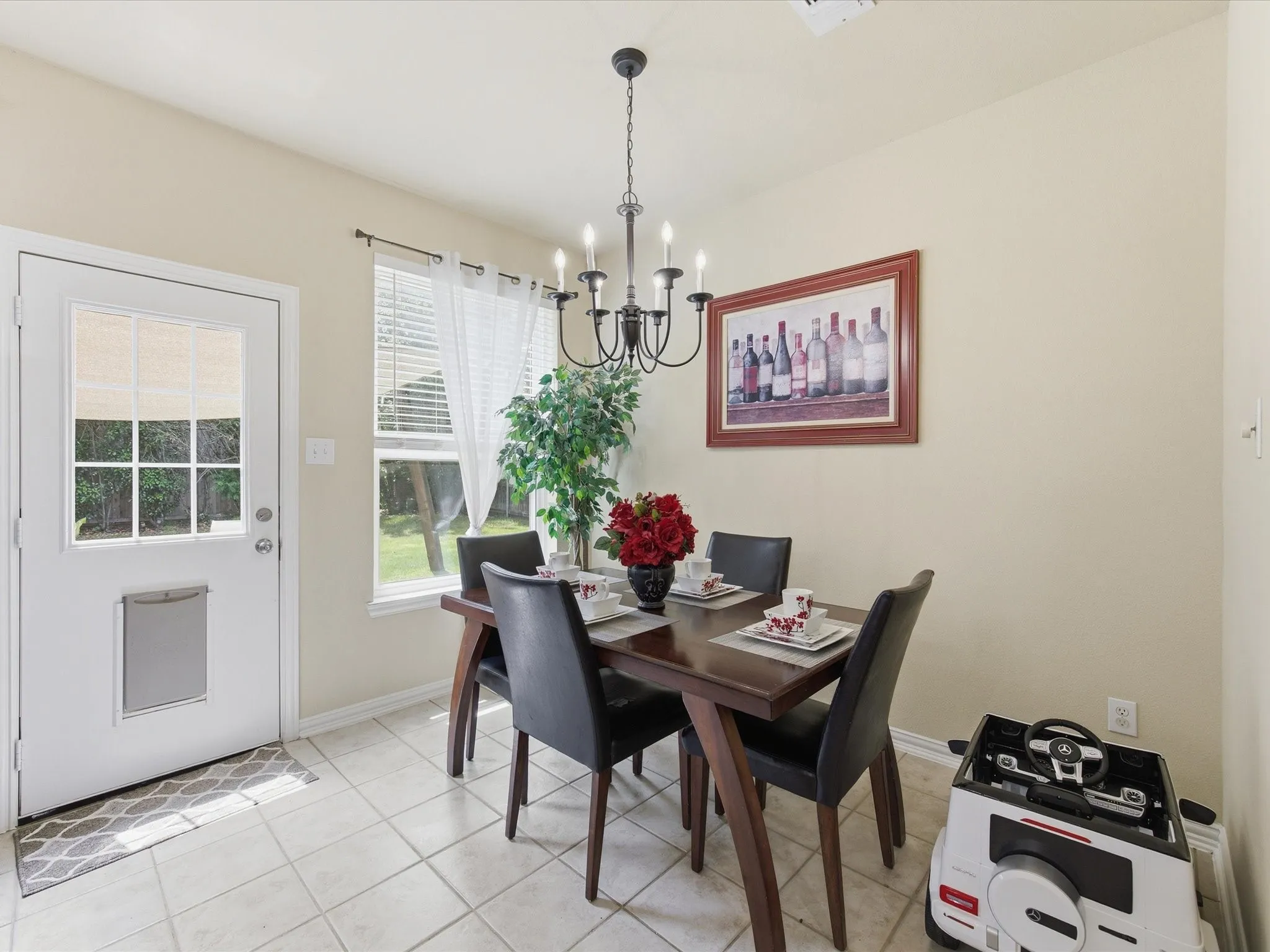 Dining area featuring neutral wall tones, square tile flooring, a white exterior door with window panes, and a window with blinds providing natural light