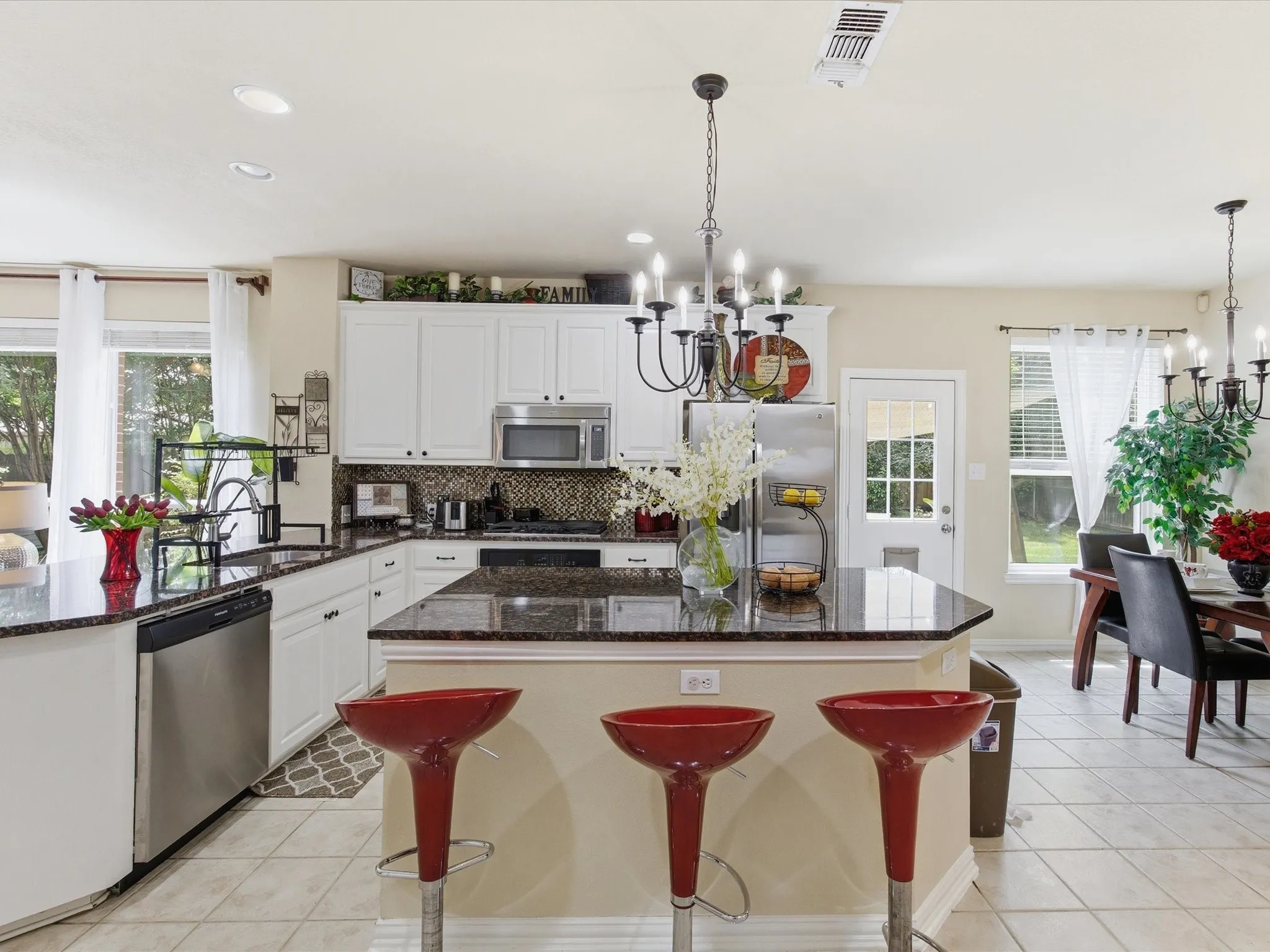 Kitchen featuring an island with seating, dark granite countertops, white cabinetry, stainless steel appliances, and tile flooring