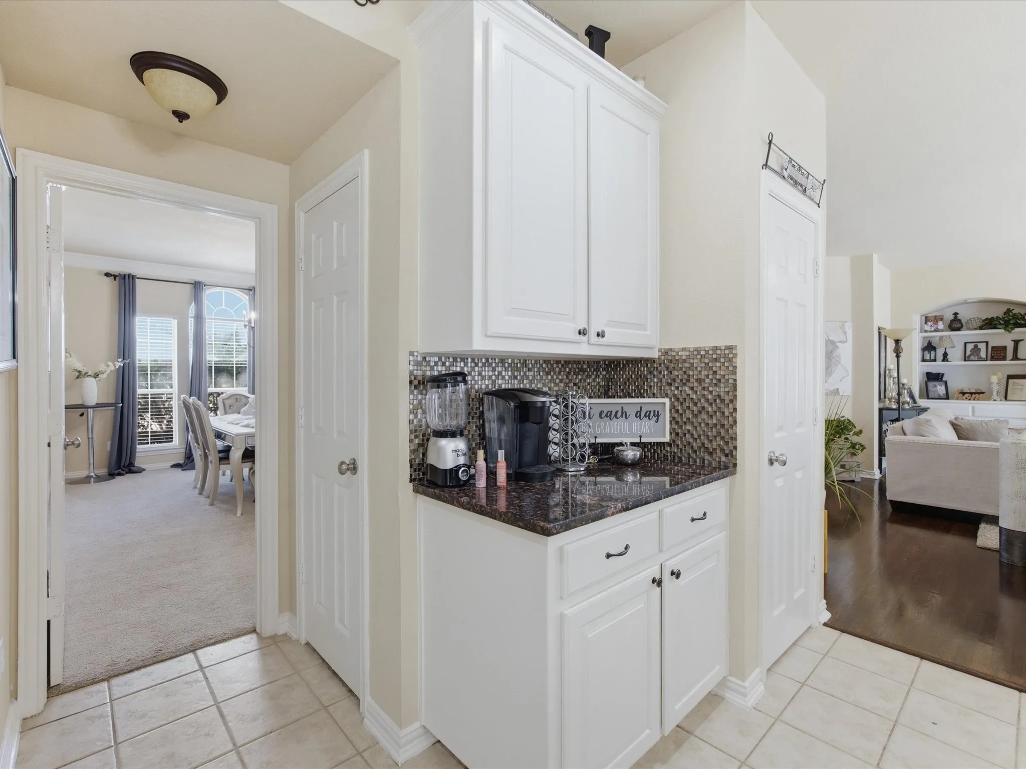 Built-in beverage station featuring white cabinetry, dark countertop, and mosaic tile backsplash
