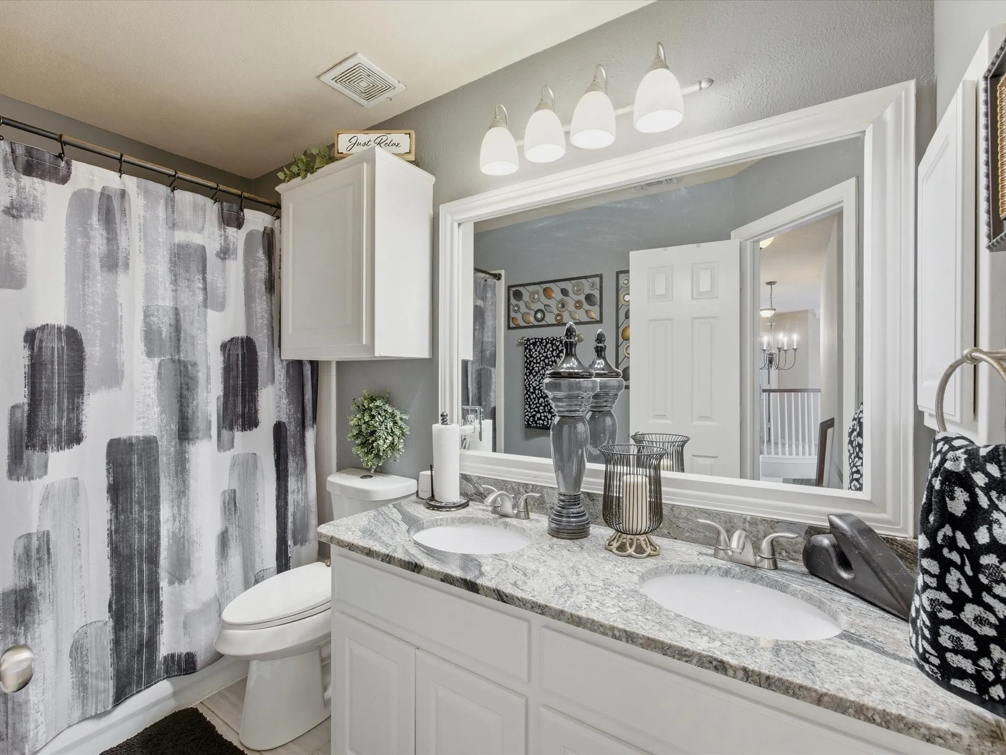 Bathroom featuring a double vanity with stone-finish countertop, dual undermount sinks, and chrome faucets