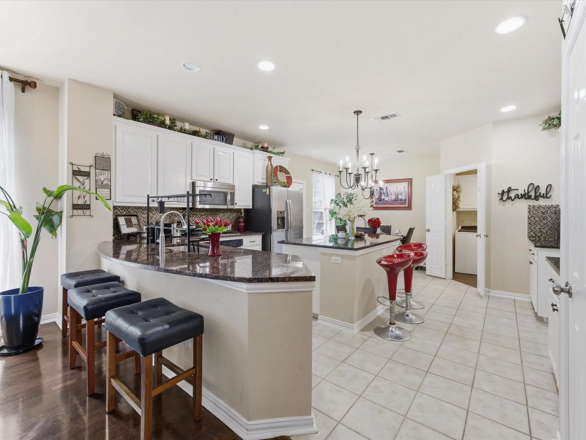 Kitchen featuring a curved granite countertop island with integrated sink, white cabinetry, and stainless steel appliances