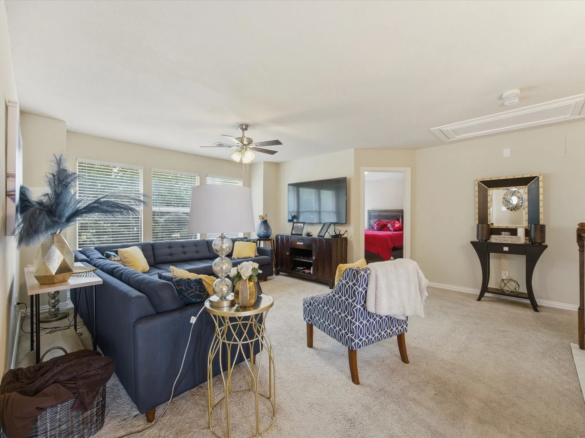 Spacious living area featuring carpet flooring, light-toned walls, and multiple windows with blinds