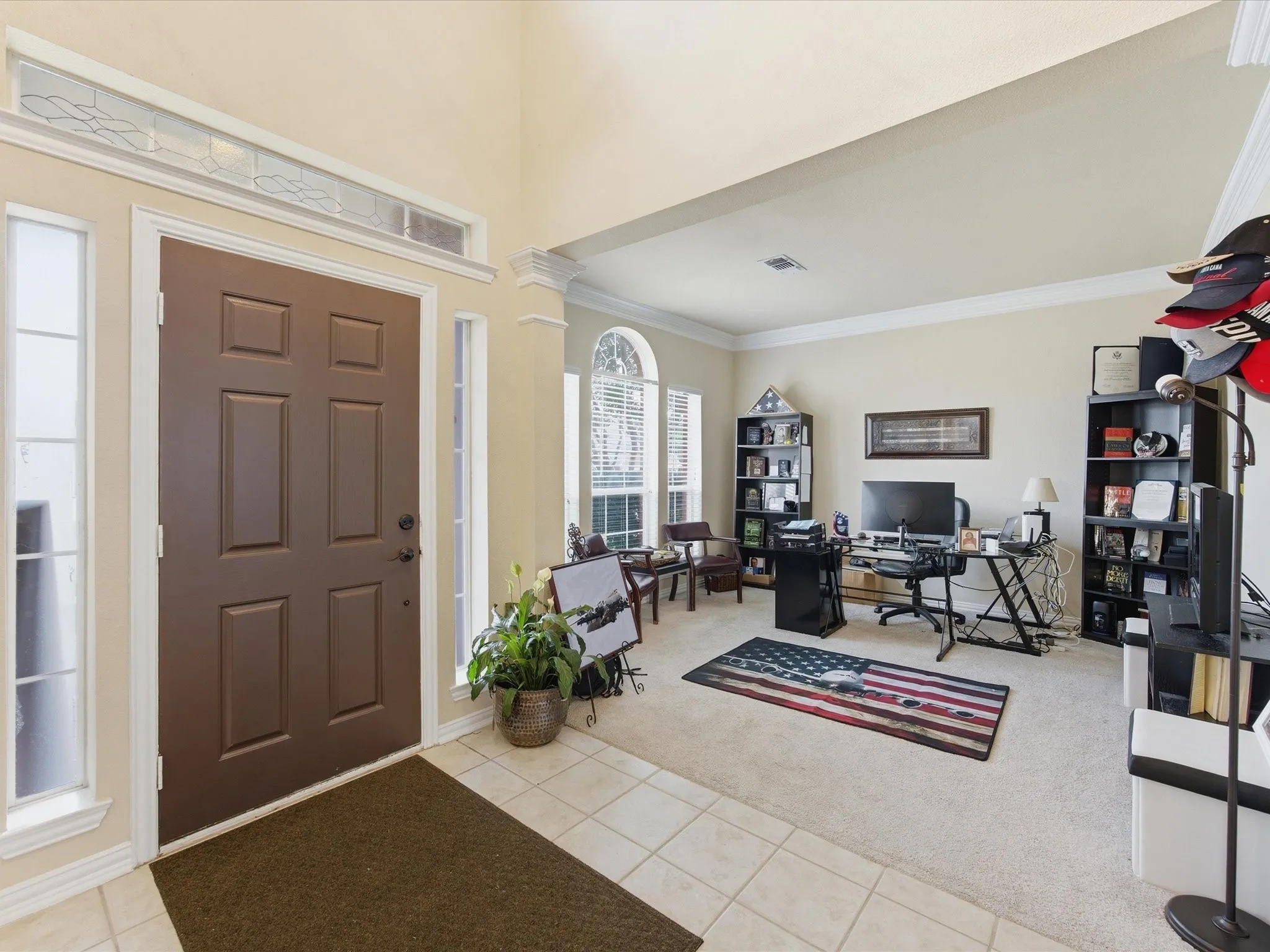 Foyer with tile flooring opening to a carpeted room with multiple windows
