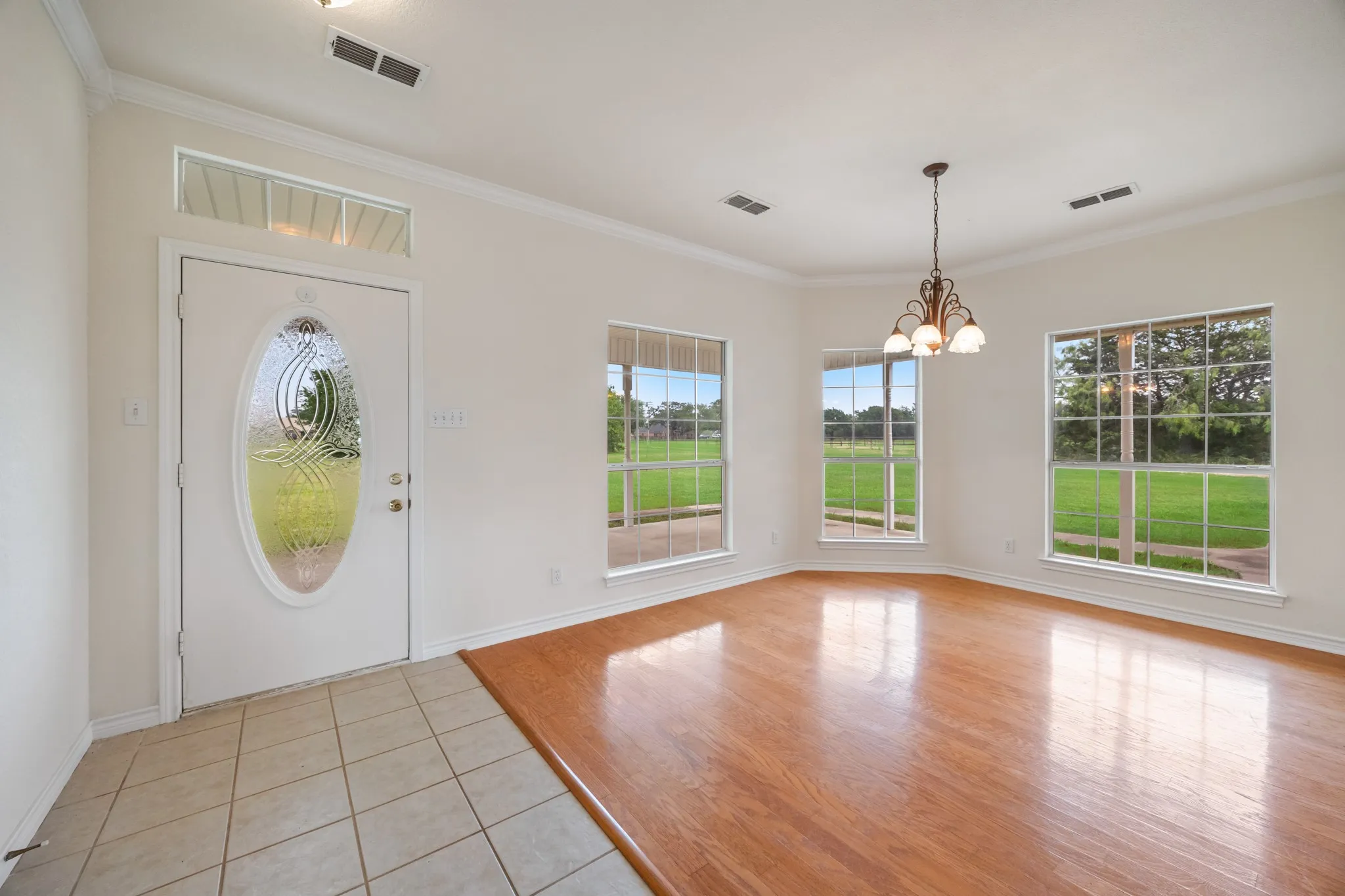 Entry area featuring a decorative glass front door with transom window, tile flooring, and wood-finish flooring extending into the adjacent space