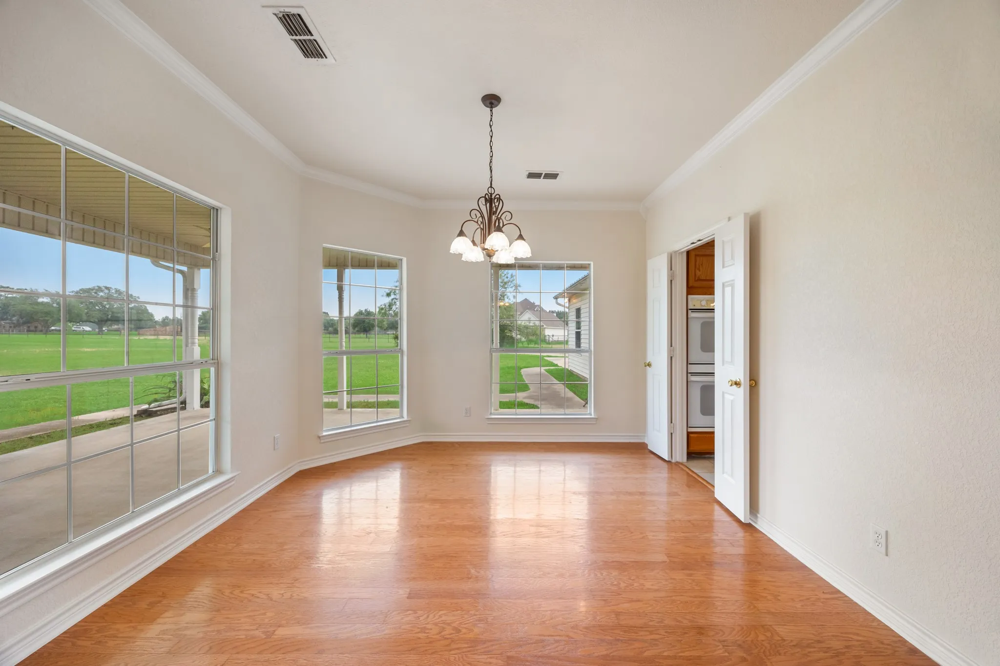 Spacious room with wood-finish flooring and multiple windows providing ample natural light