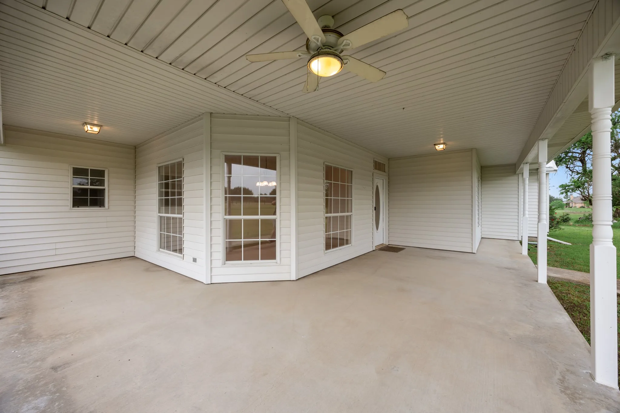 Expansive covered patio featuring a concrete surface and white vinyl siding