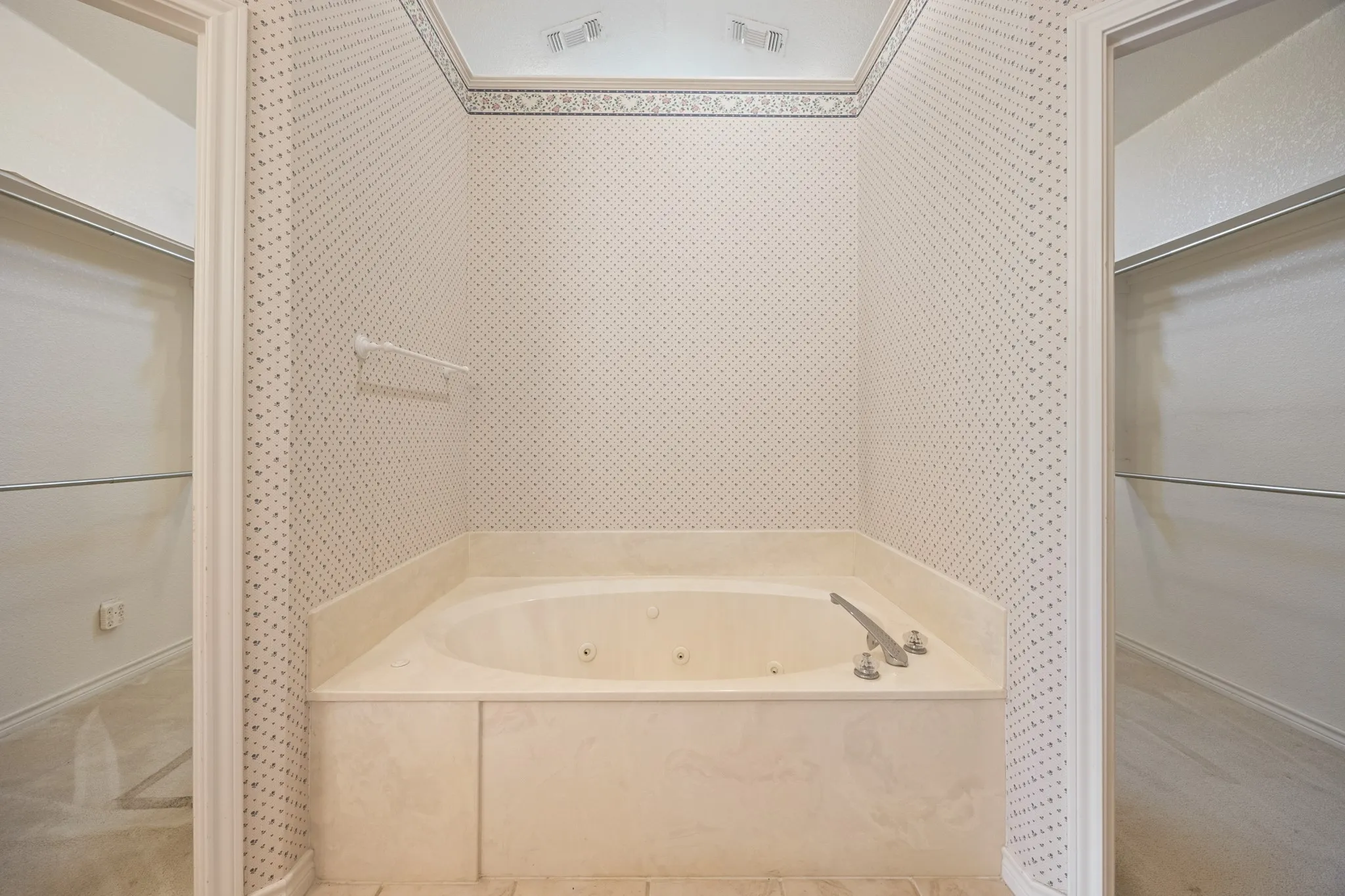 Alcove soaking tub with integrated jets surrounded by patterned wallpaper