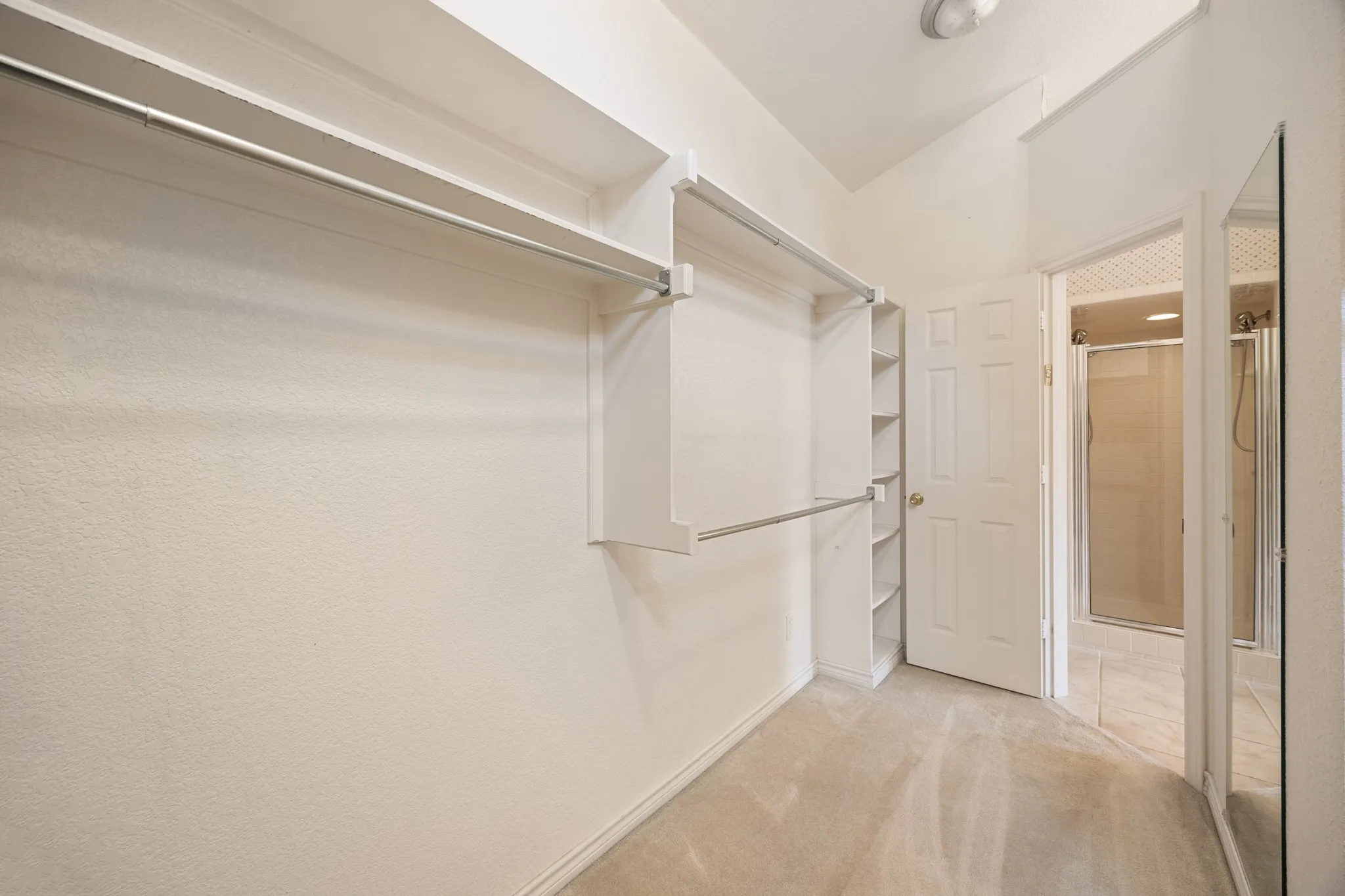 Spacious walk-in closet featuring built-in shelving, multiple hanging rods, and carpet flooring