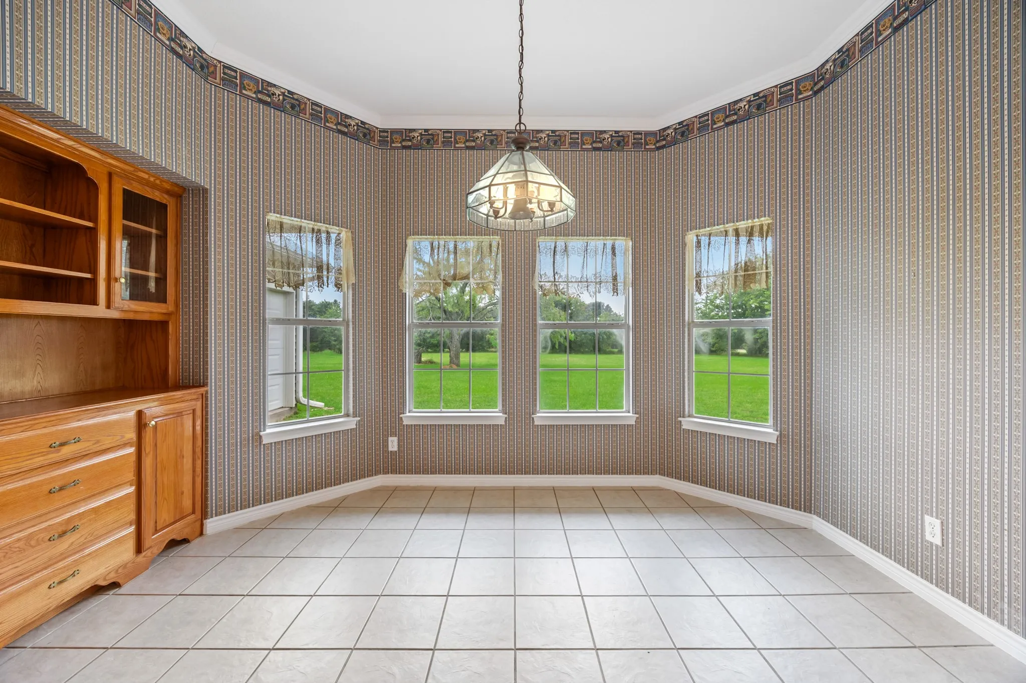 Bay window with four individual windows, complete with tile flooring and a built-in wooden cabinet