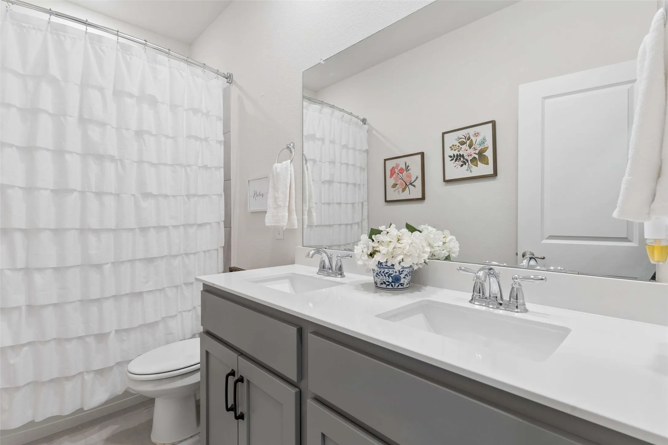Dual sink vanity featuring a light countertop and chrome fixtures