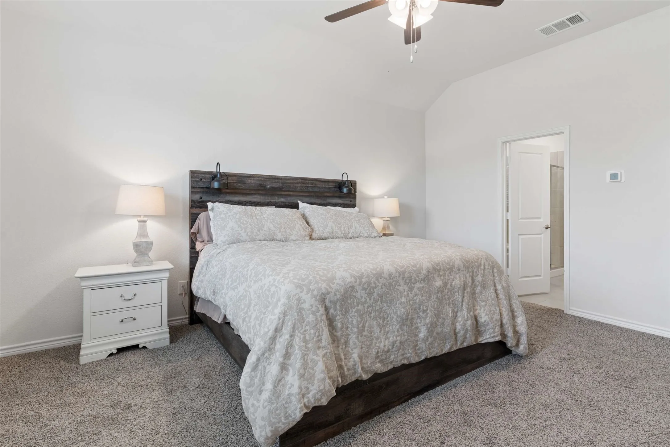 Carpeted bedroom with a vaulted ceiling and ceiling fan
