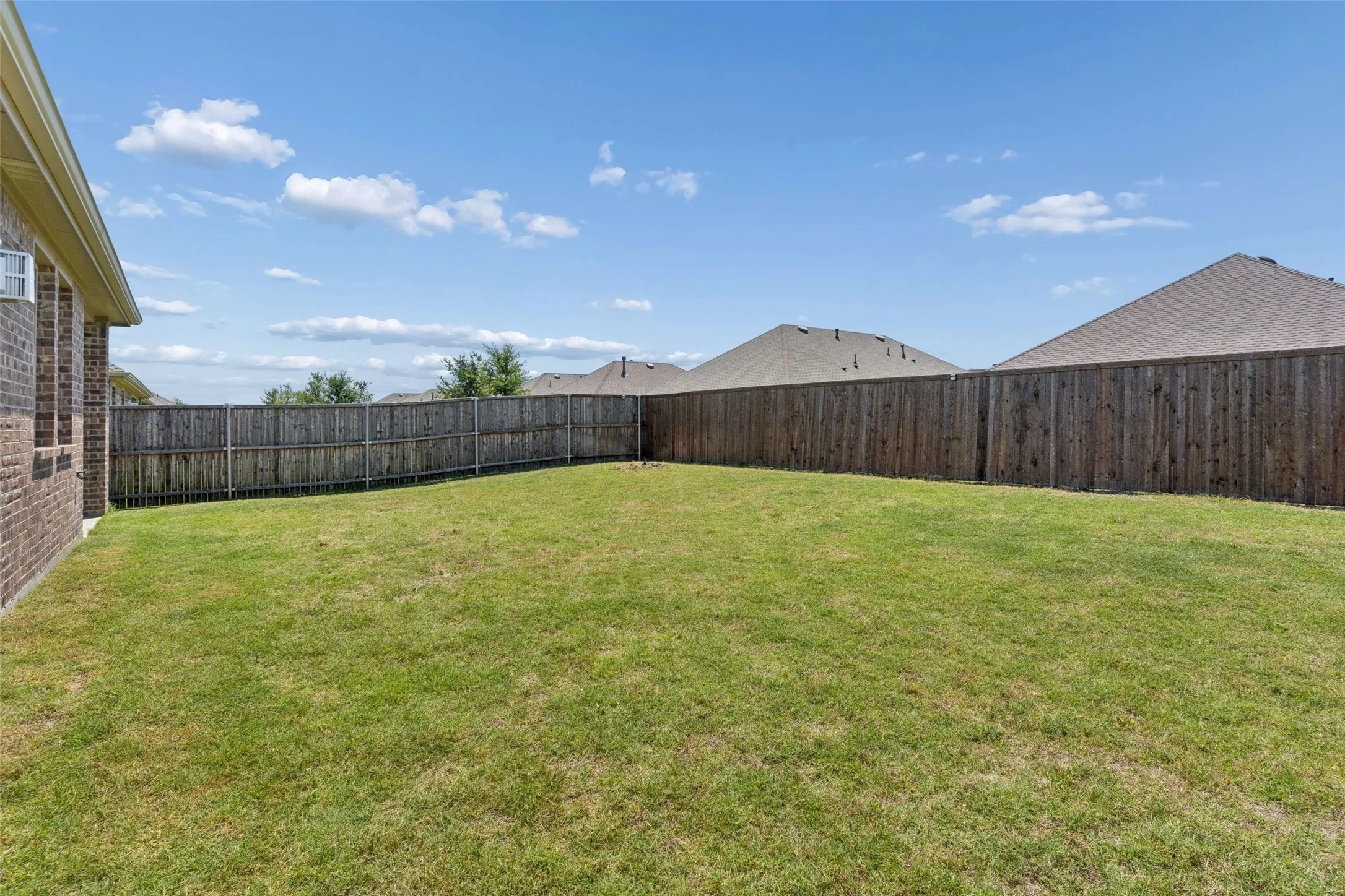 Expansive lawn area featuring a full privacy fence
