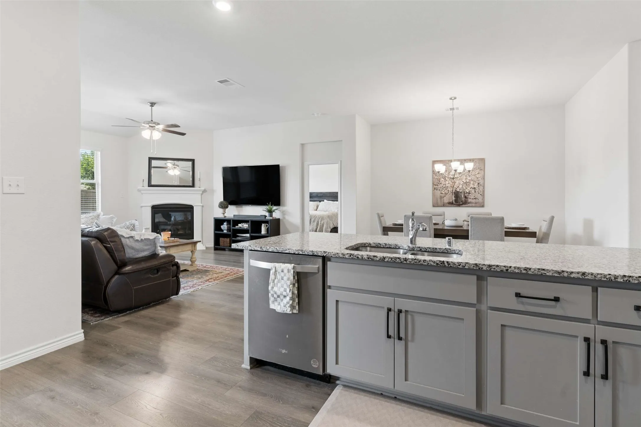 Kitchen island with a granite-style countertop and undermount sink, complemented by gray shaker cabinetry and stainless steel appliances