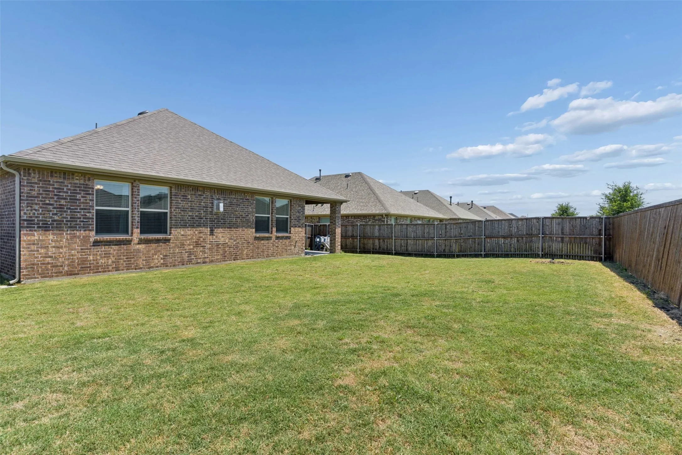 Expansive grassy backyard featuring a full privacy fence
