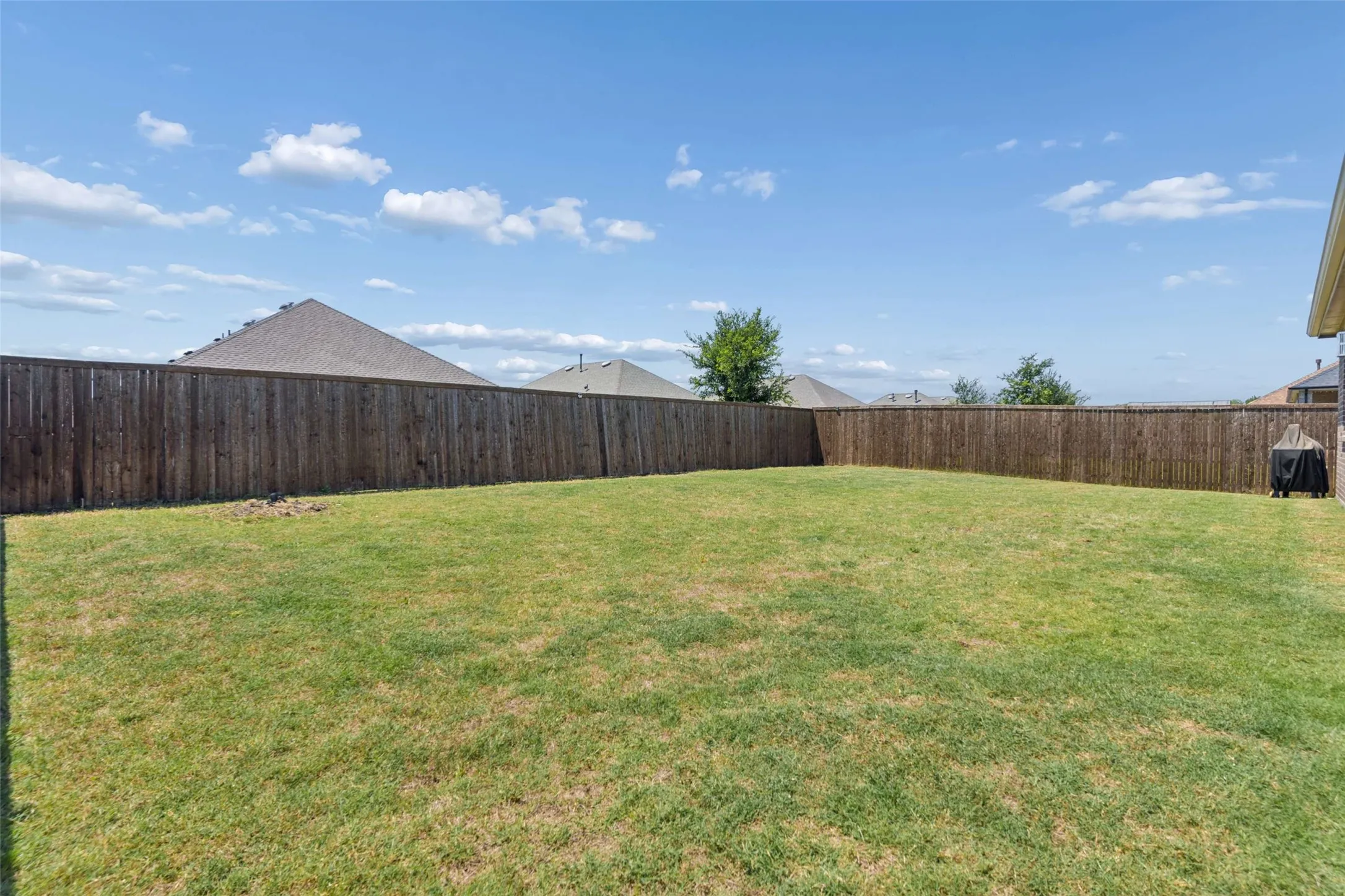 Spacious backyard featuring a full perimeter wood privacy fence and a broad expanse of lawn