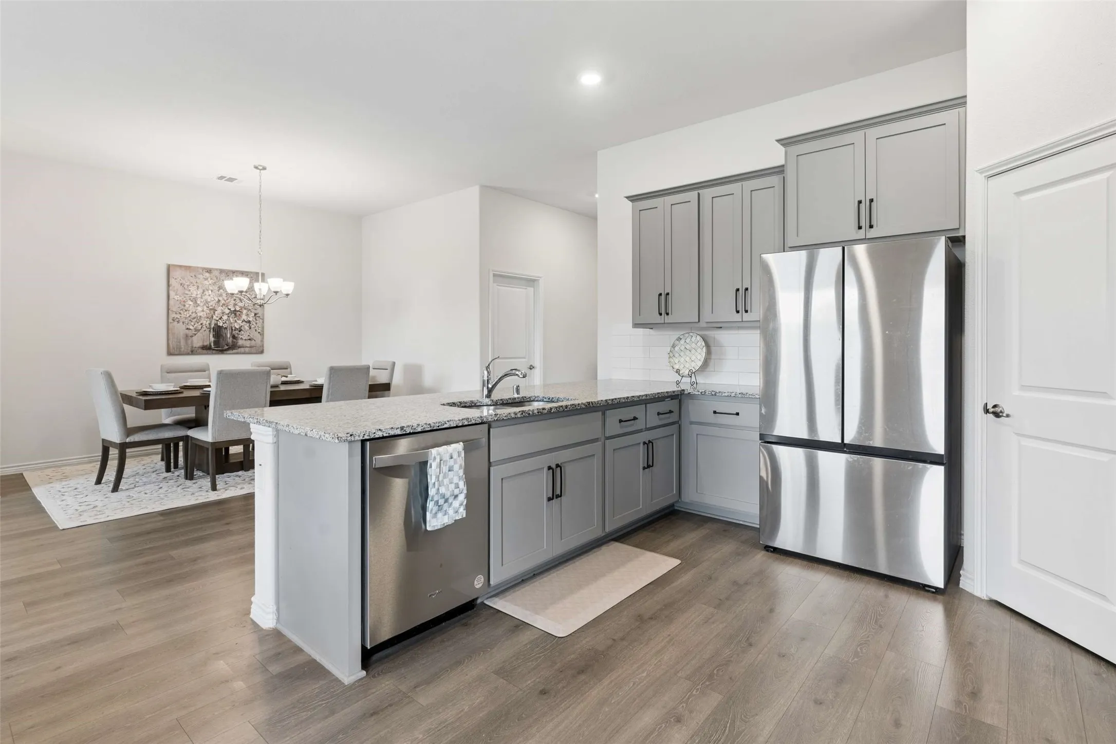 Kitchen with gray cabinetry, stainless steel appliances, granite countertops, and wood-finish flooring