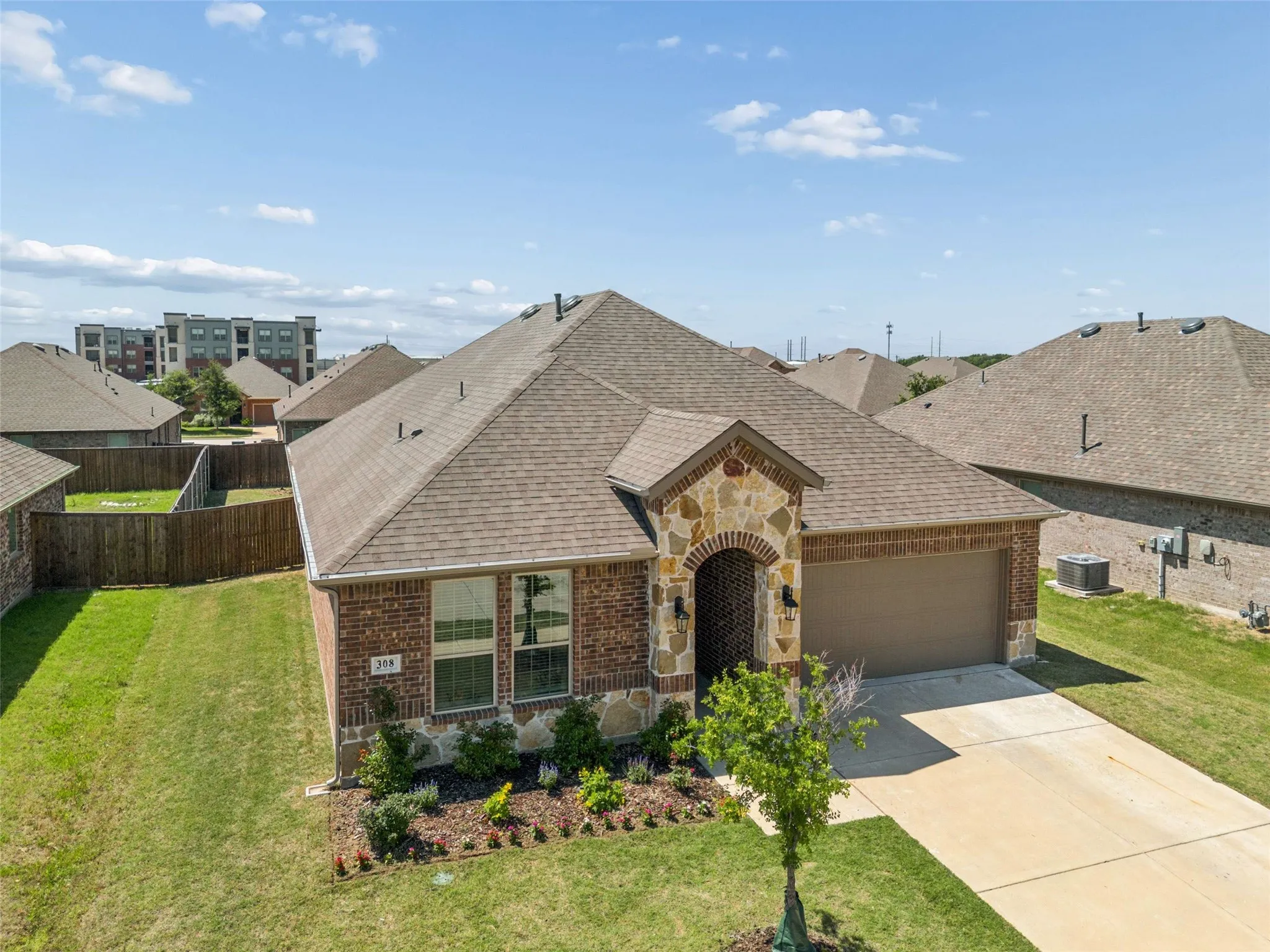 Single-story residence featuring a brick and stone facade, an arched entryway, and an attached two-car garage