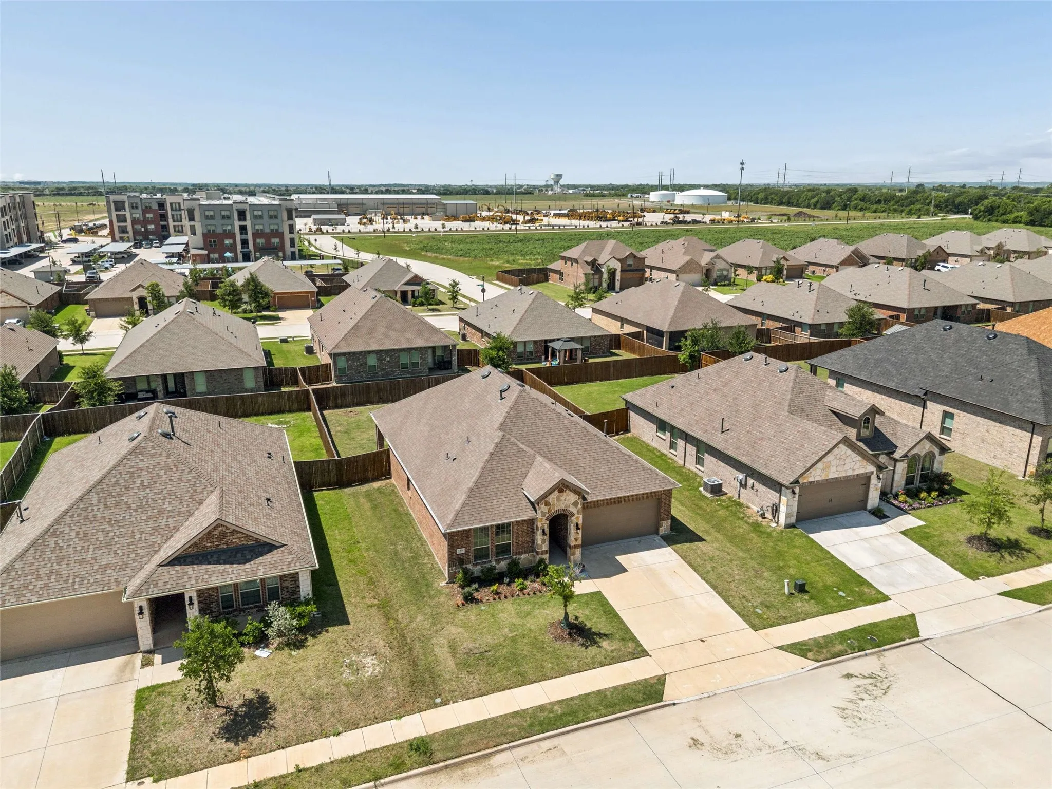 Aerial view showcasing a residential neighborhood with single-story homes featuring brick and stone facades