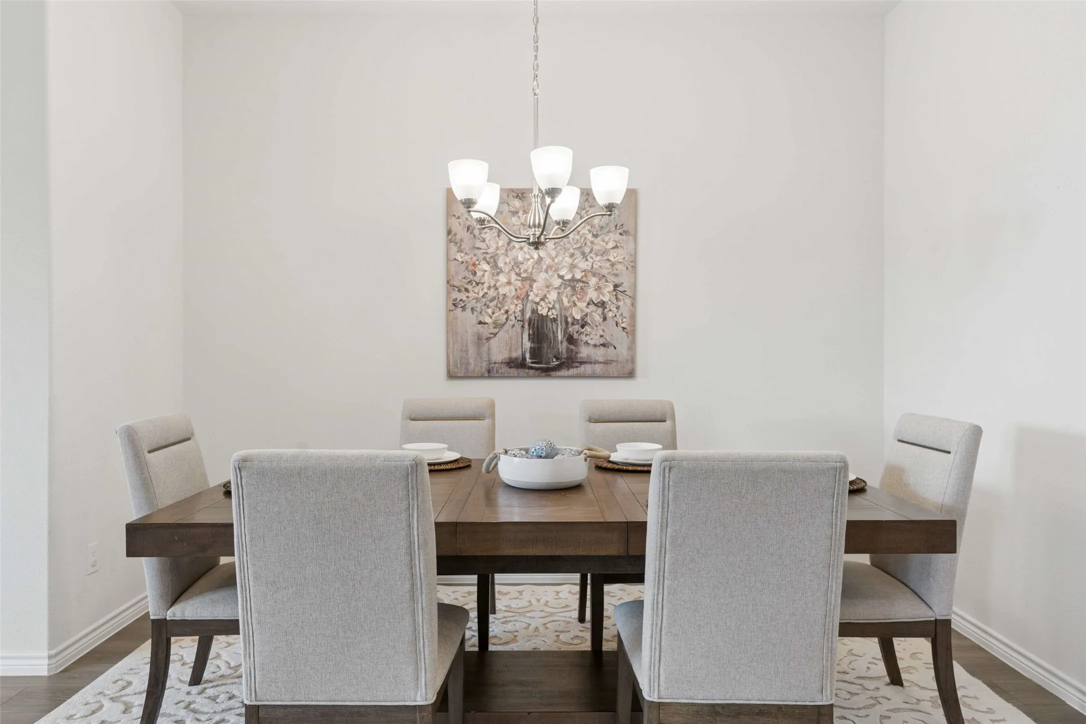Dining area featuring a five-light chandelier, light wood-finish flooring, and crisp white walls